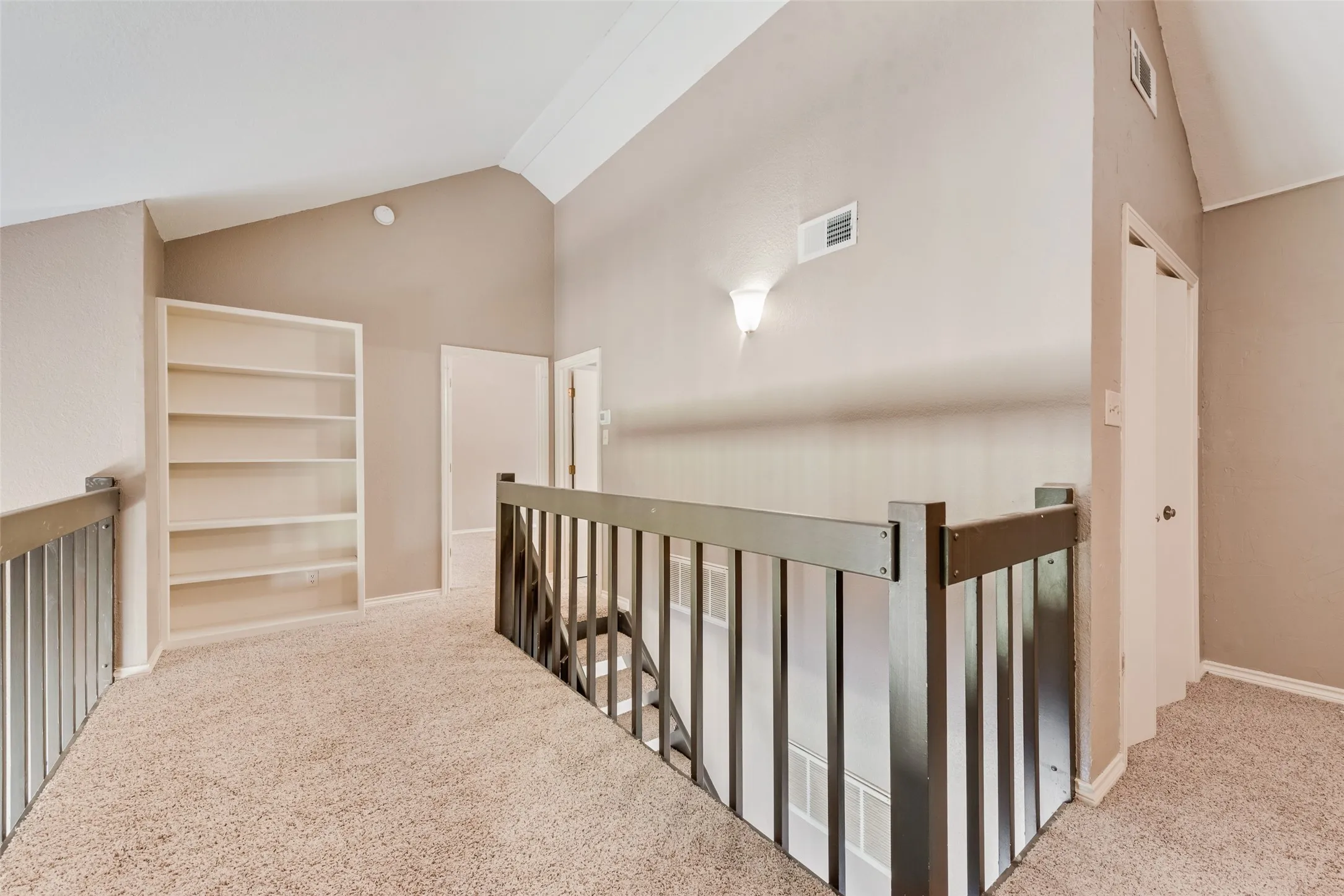 Corridor featuring light carpet, high vaulted ceiling, and an upstairs landing