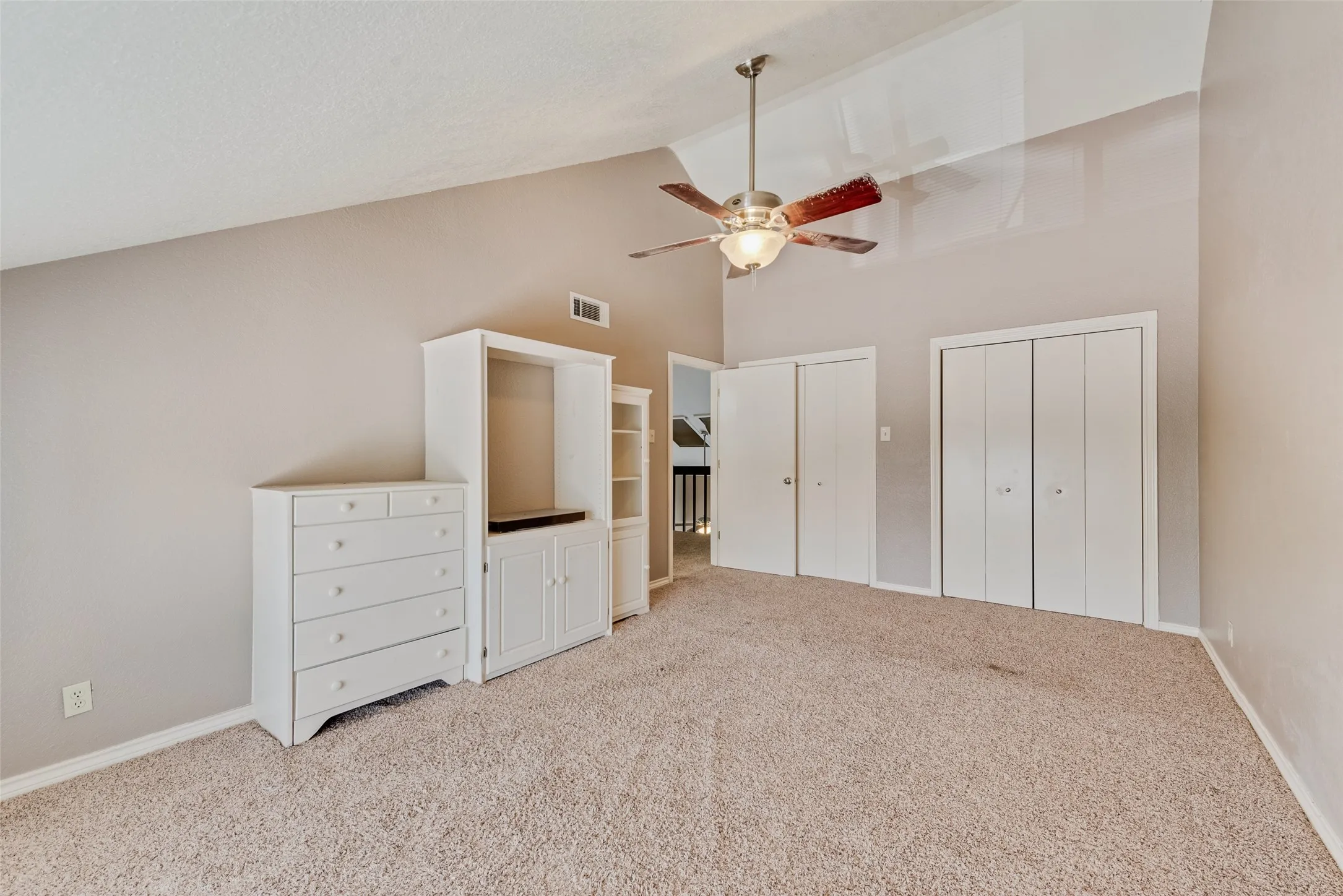 Unfurnished bedroom with two closets, high vaulted ceiling, carpet floors, and a ceiling fan