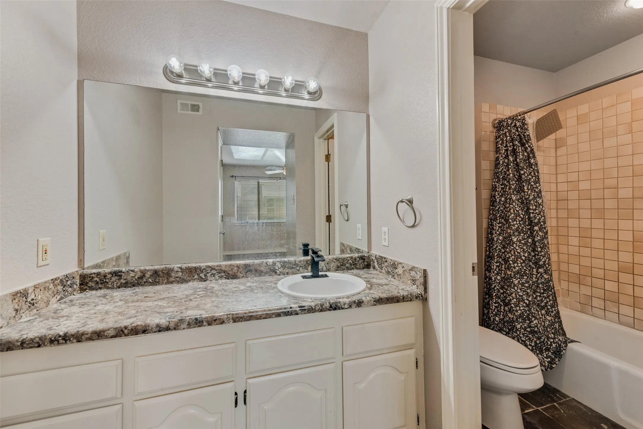 Full bathroom with vanity, shower / tub combo with curtain, and a textured wall