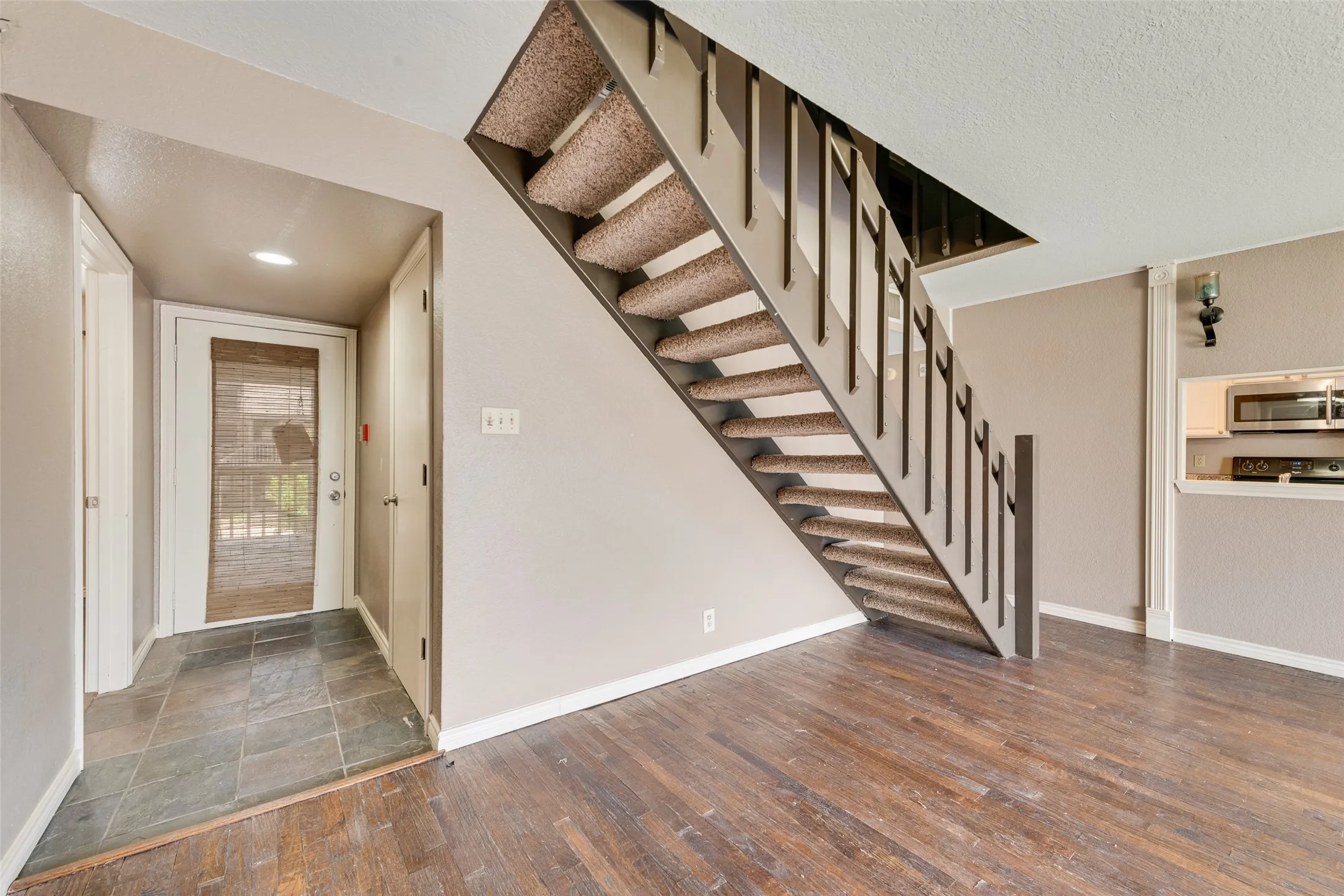 Entryway featuring stairway, a textured ceiling, and dark wood finished floors