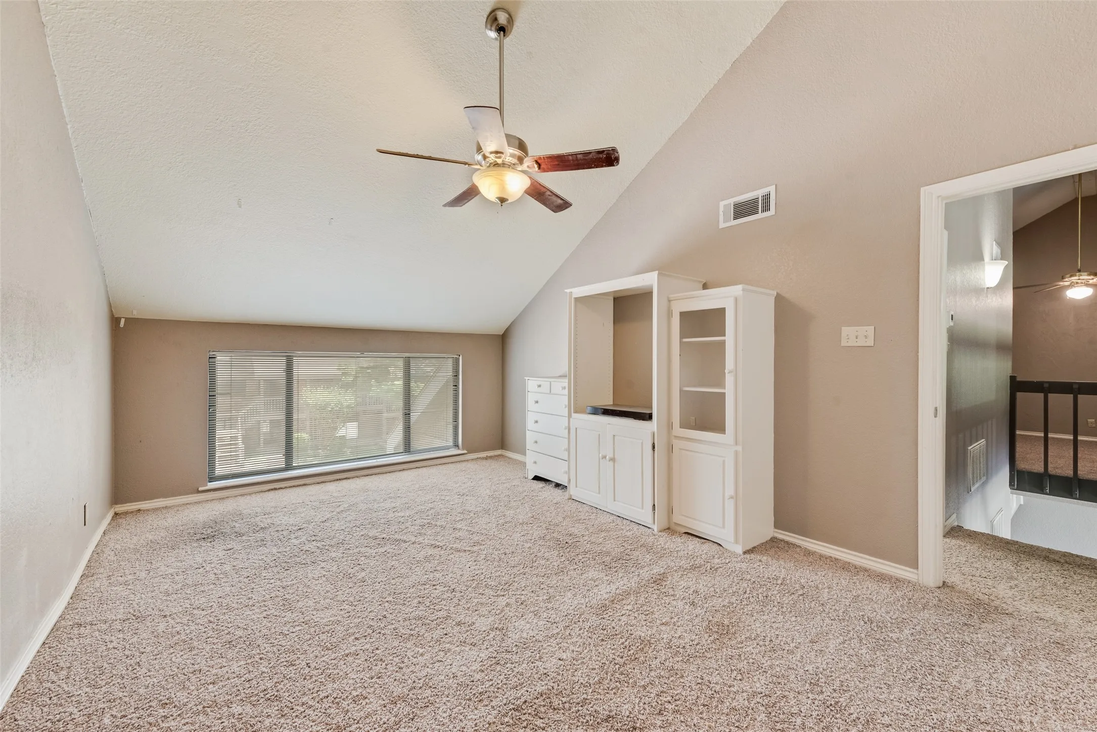 Unfurnished living room featuring a ceiling fan, carpet flooring, high vaulted ceiling, and a textured ceiling