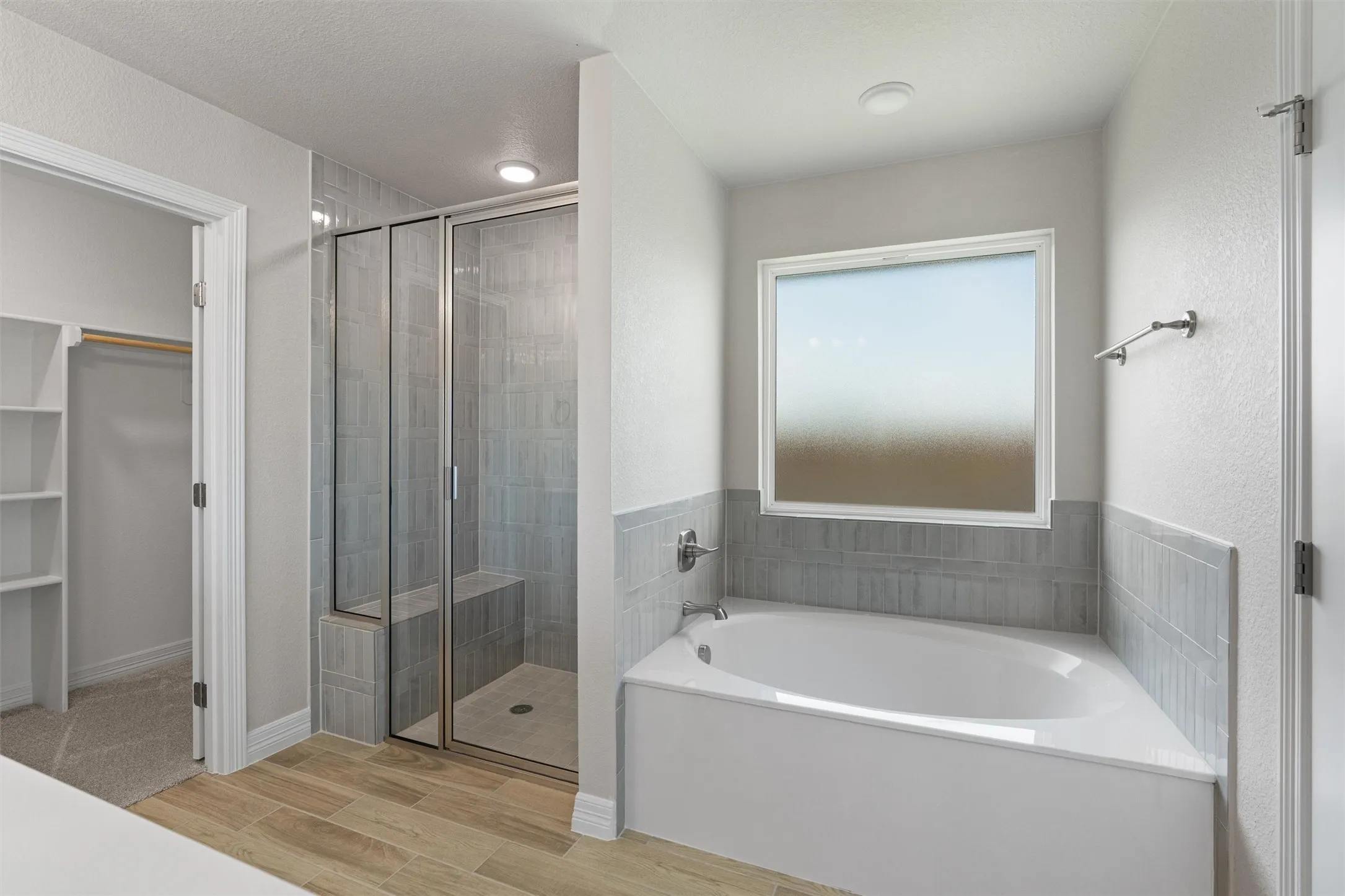 Spacious bathroom featuring a corner soaking tub, a walk-in shower with a built-in bench, and wood-finish tile flooring