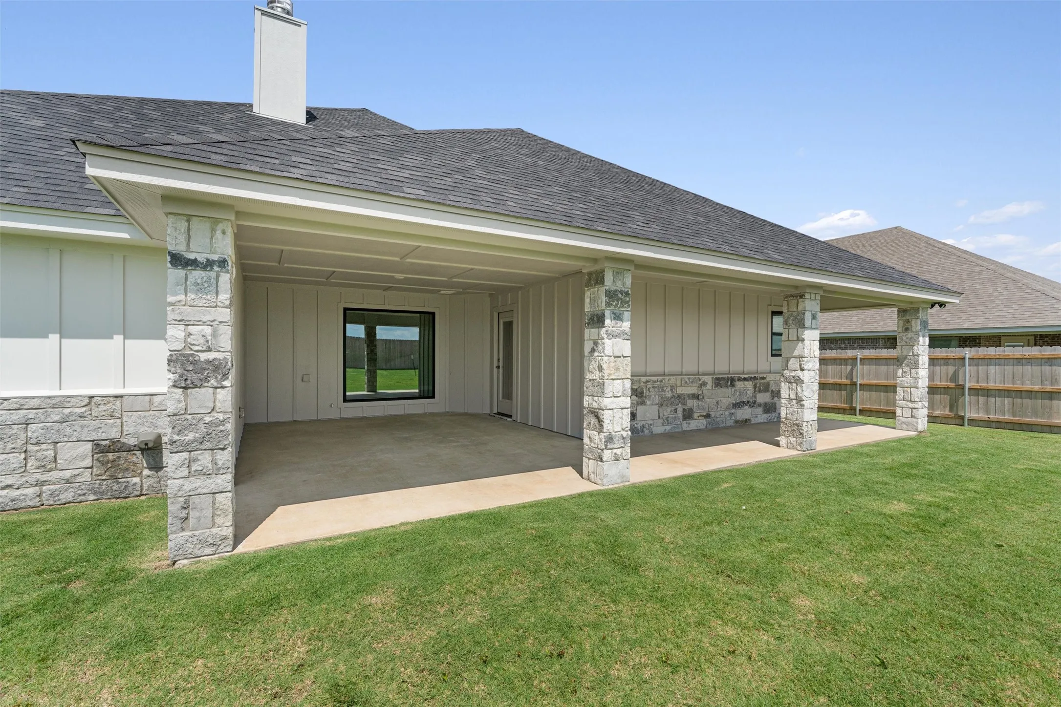 Covered patio with stone-clad columns and a concrete surface
