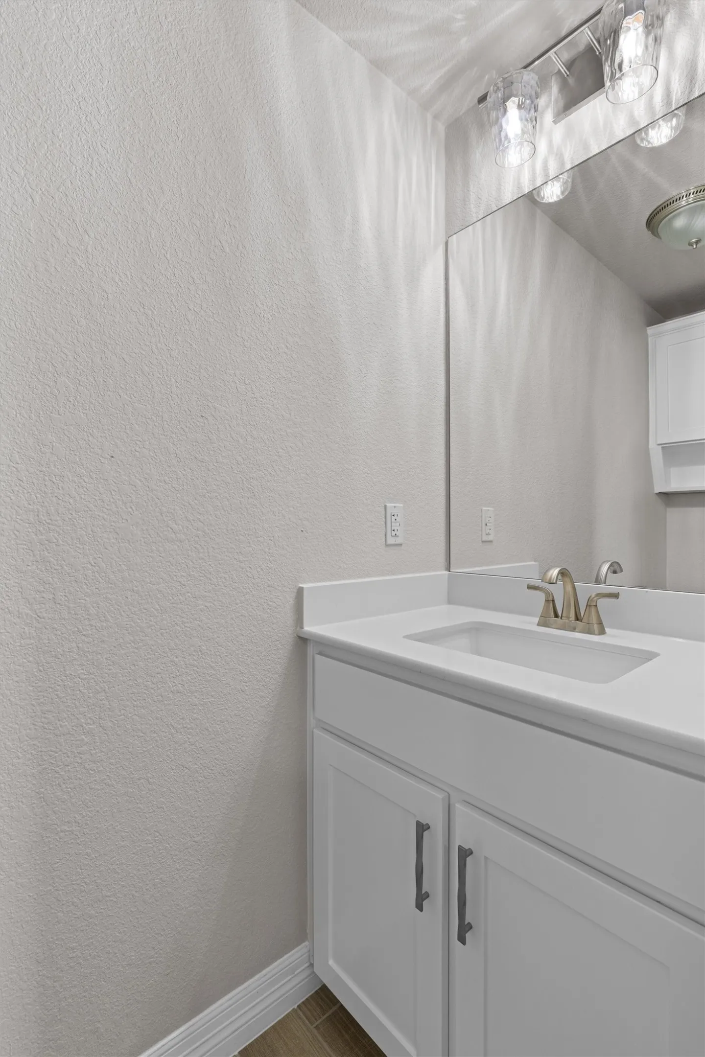 Bathroom vanity featuring white cabinetry, a single basin sink, and a brushed nickel faucet