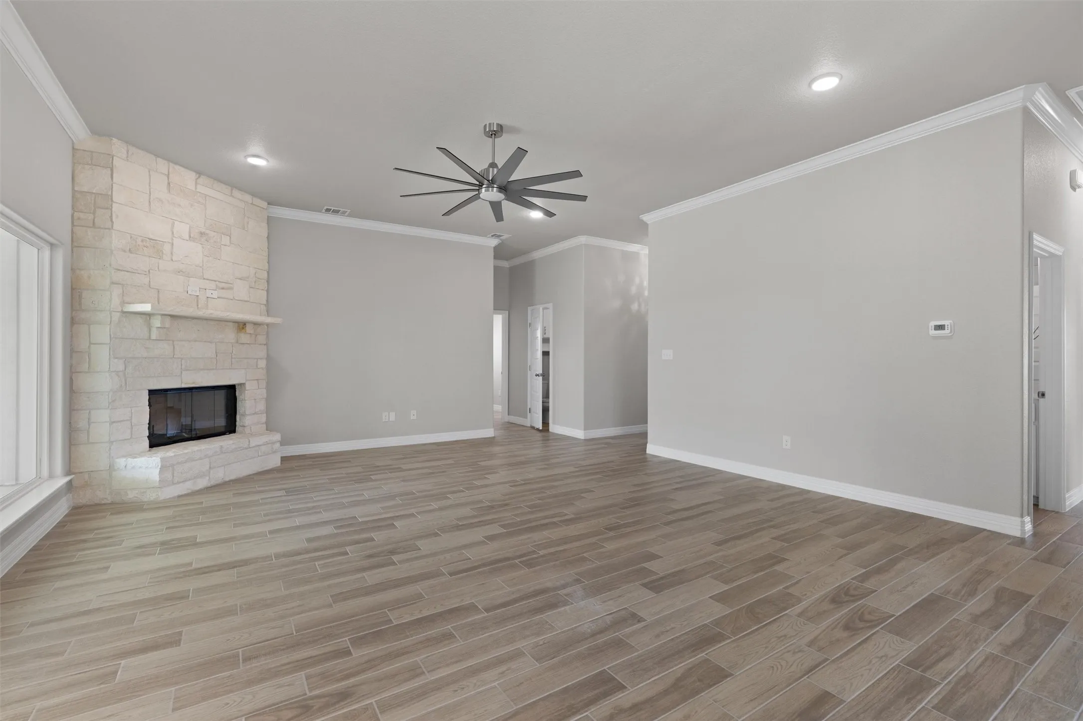 Living area featuring a stone-clad fireplace with mantel, wood-finish flooring, recessed lighting, and a contemporary ceiling fan
