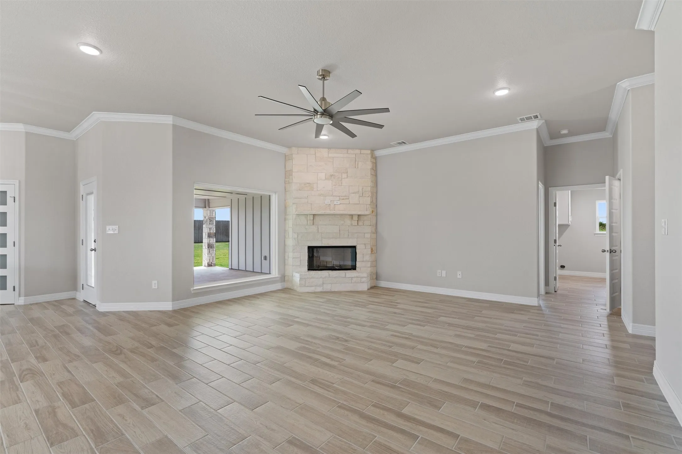 Spacious living area featuring light wood-finish flooring, a stone-clad fireplace with an integrated firebox, a ceiling fan, and recessed lighting