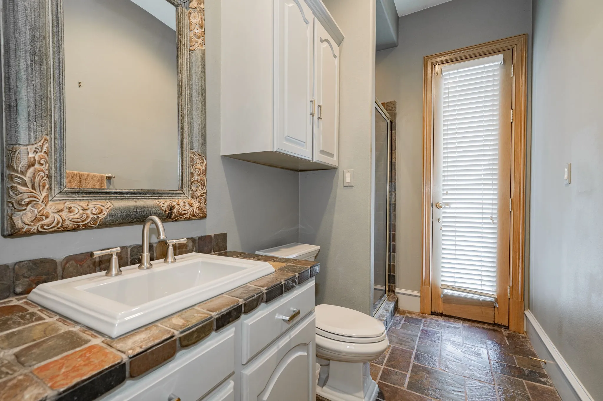 Bathroom with stone tile floors, vanity, and a stall shower