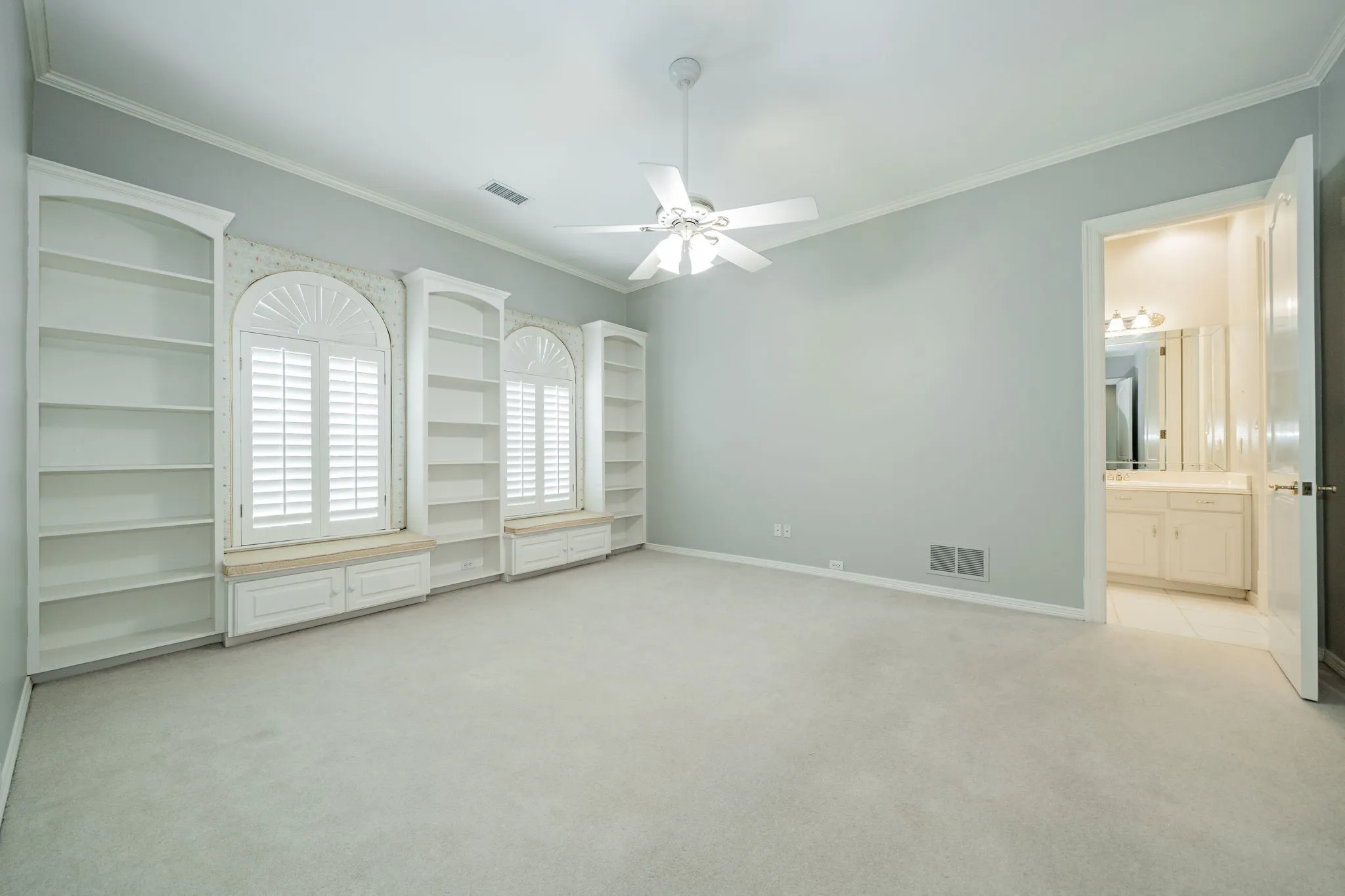 Empty room with crown molding, light colored carpet, and a ceiling fan