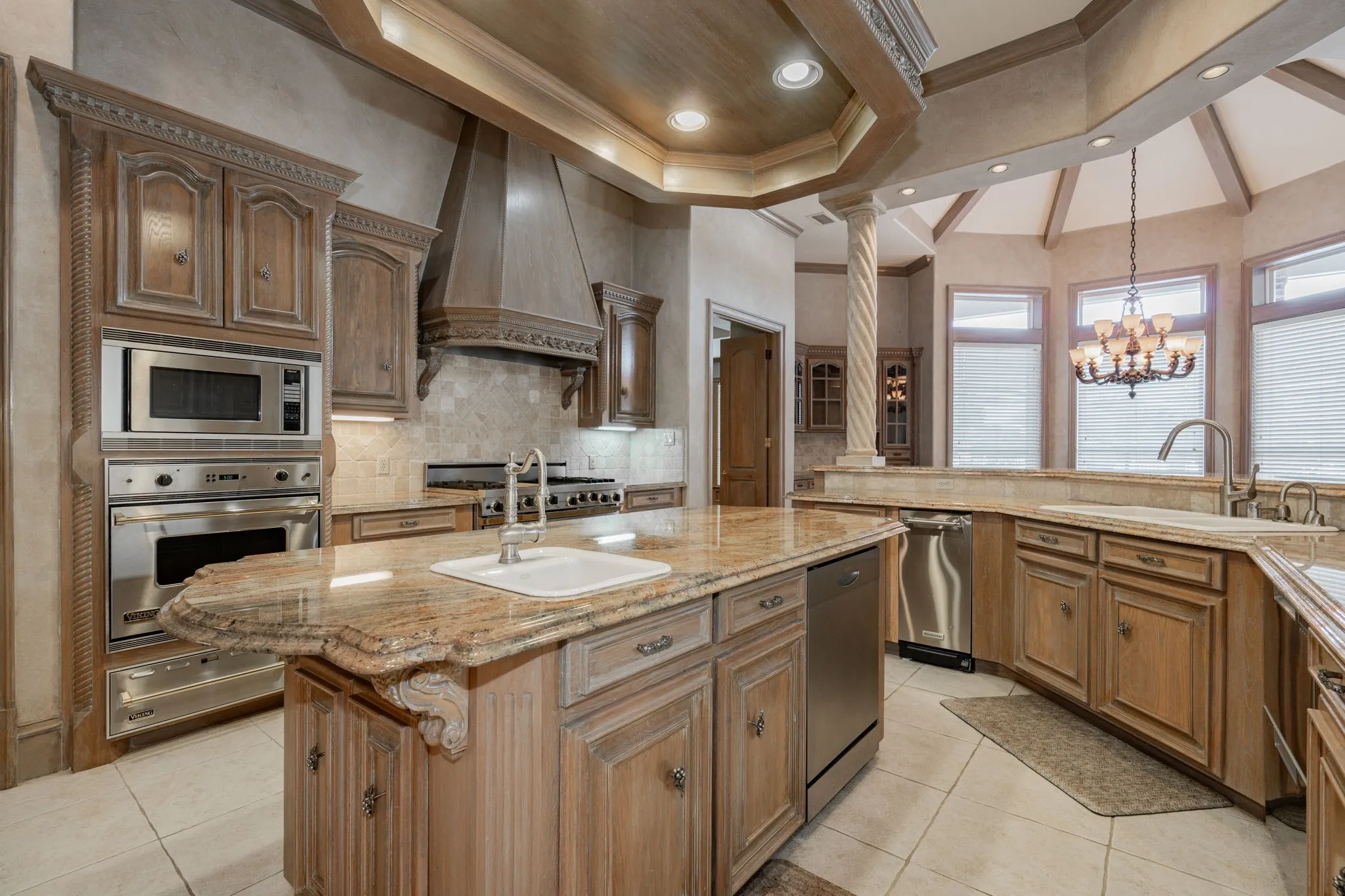 Kitchen with tasteful backsplash, a center island with sink, appliances with stainless steel finishes, brown cabinets, and decorative light fixtures