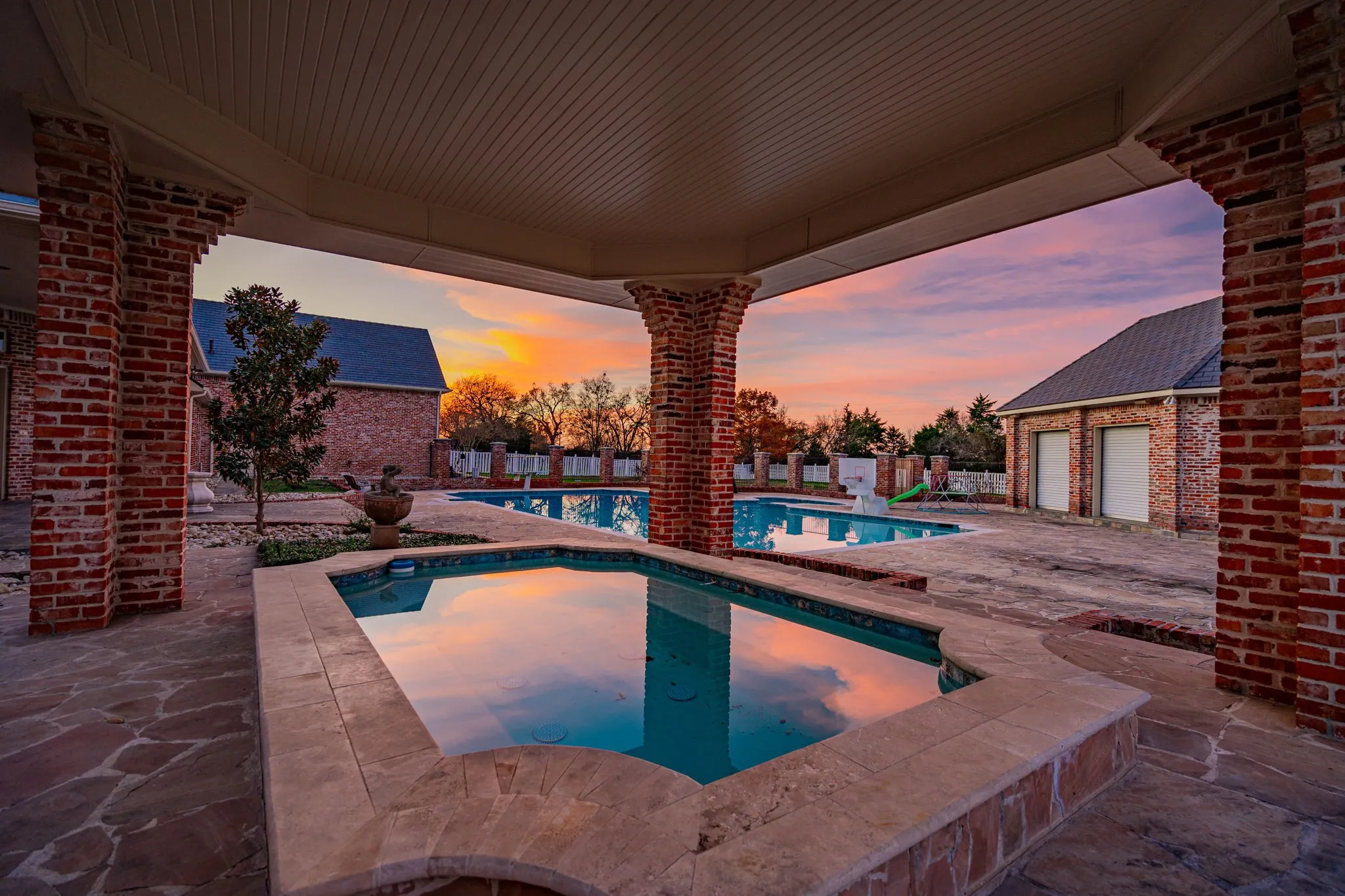 Pool at dusk featuring an in-ground hot tub, a patio, and a fenced backyard