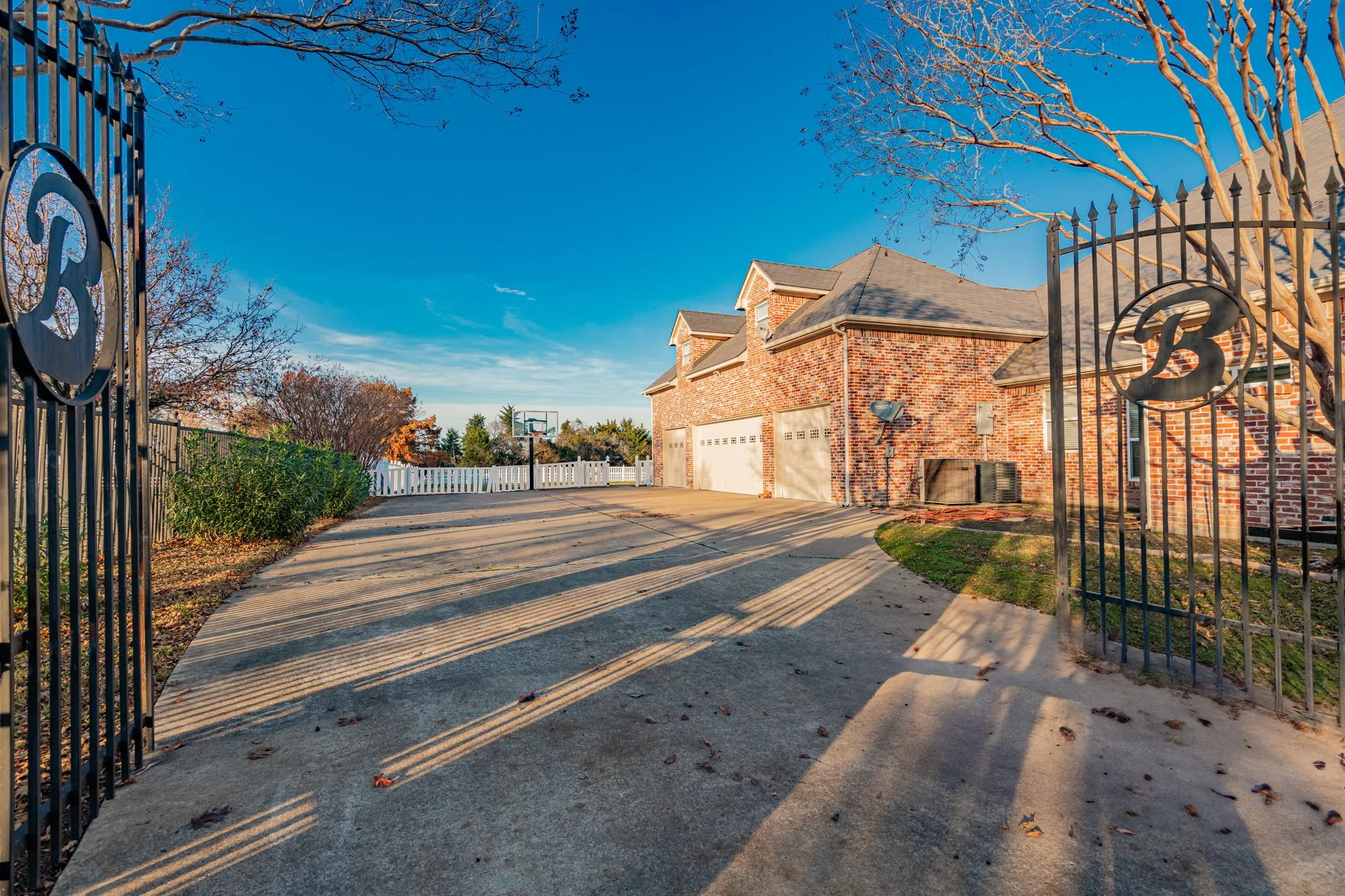 View of asphalt driveway featuring a gated entry and a gate