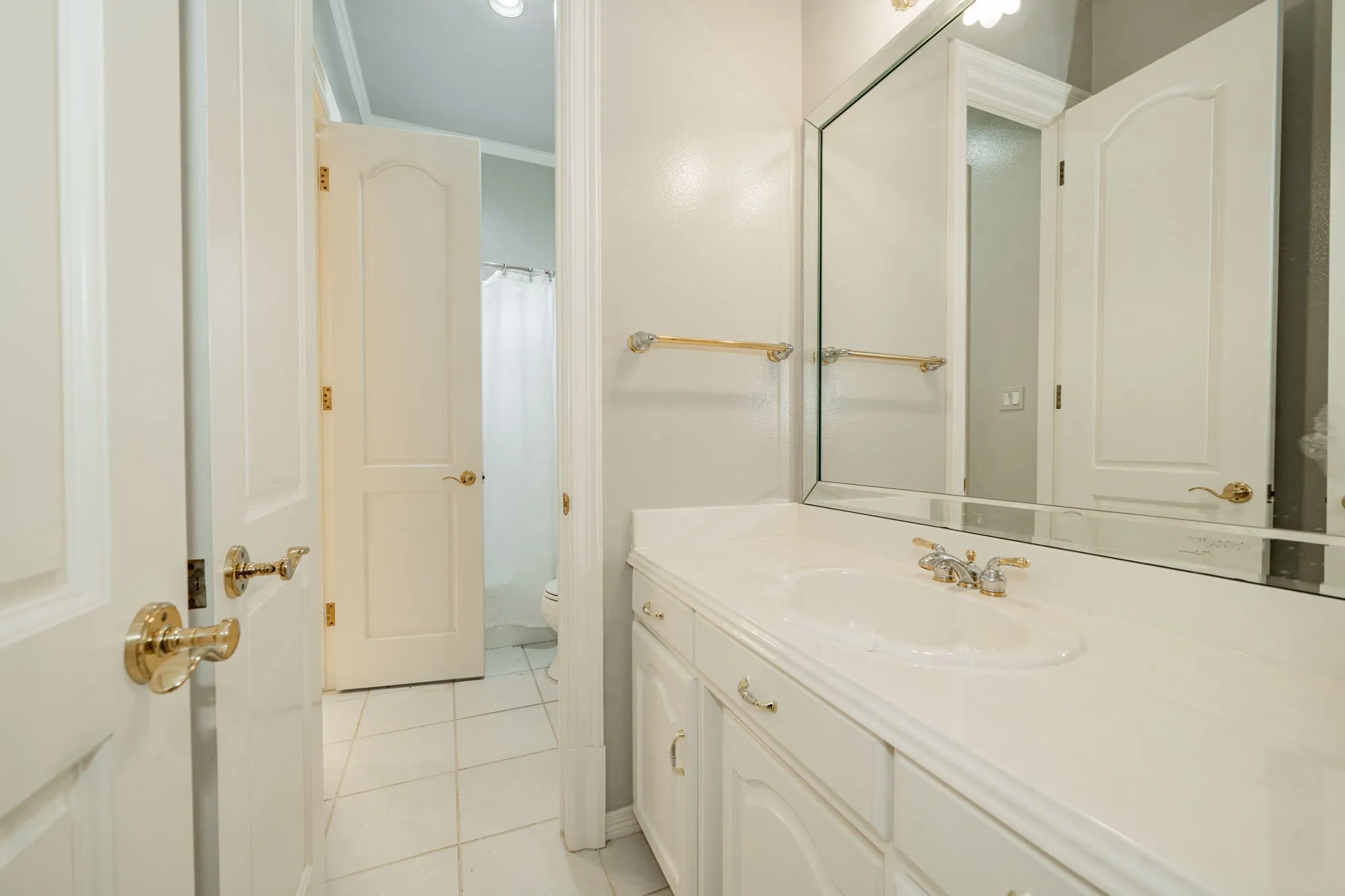 Bathroom featuring vanity, light tile patterned flooring, curtained shower, and ornamental molding