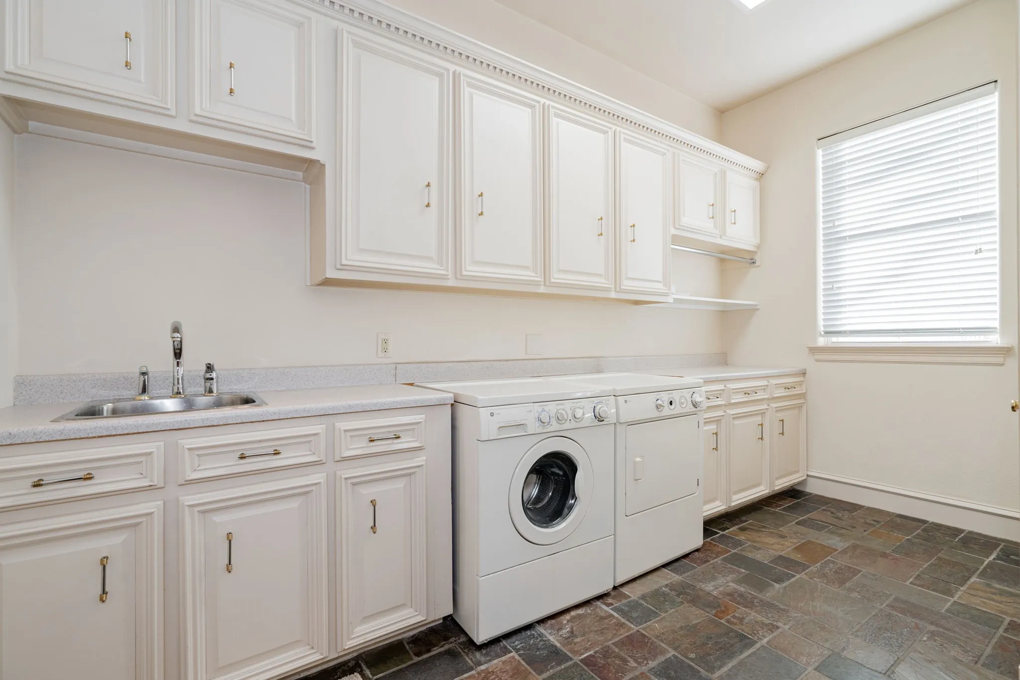 Laundry room featuring stone tile floors, washer and clothes dryer, and cabinet space