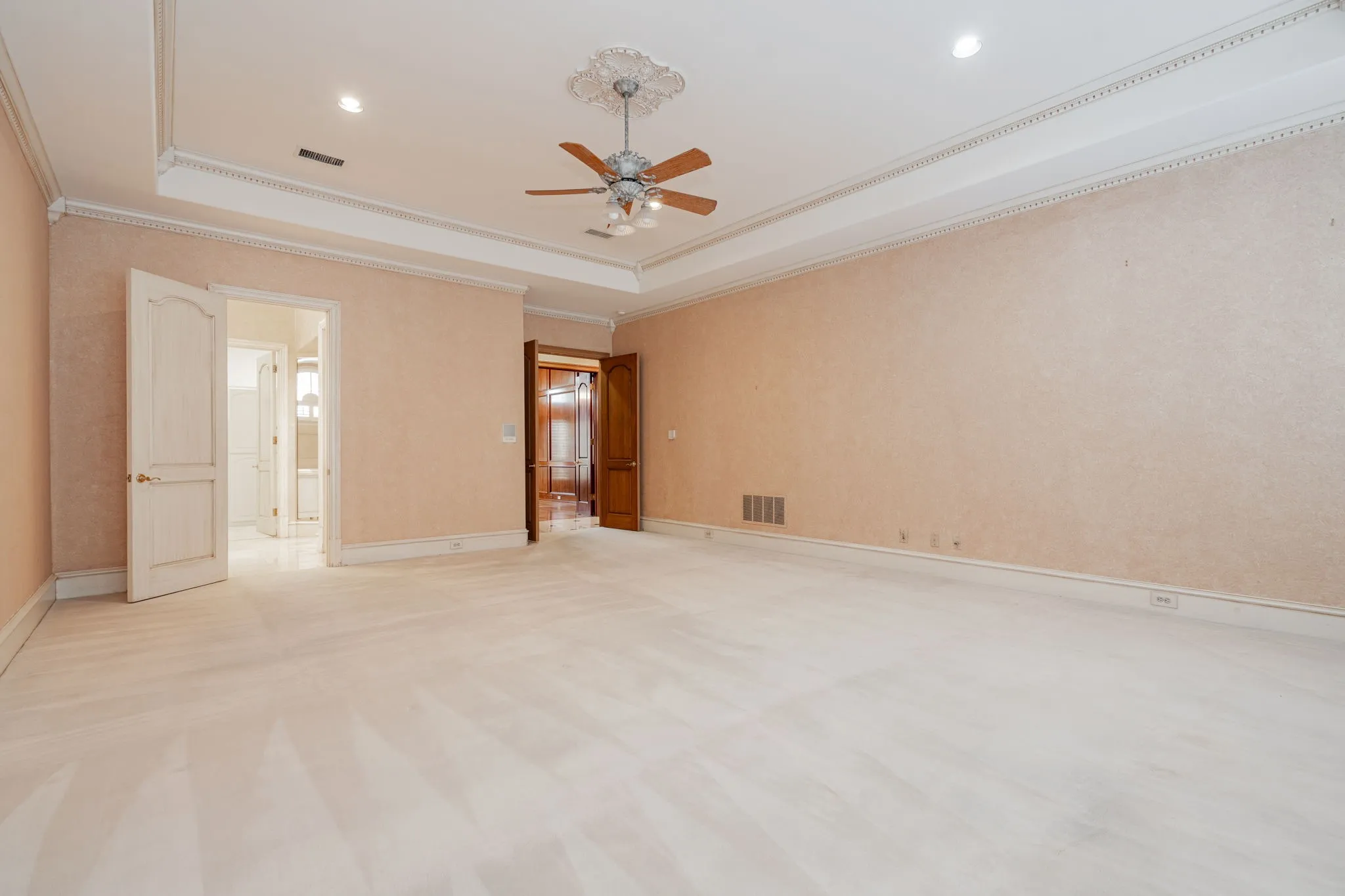 Unfurnished bedroom featuring a raised ceiling, ornamental molding, a ceiling fan, and carpet floors