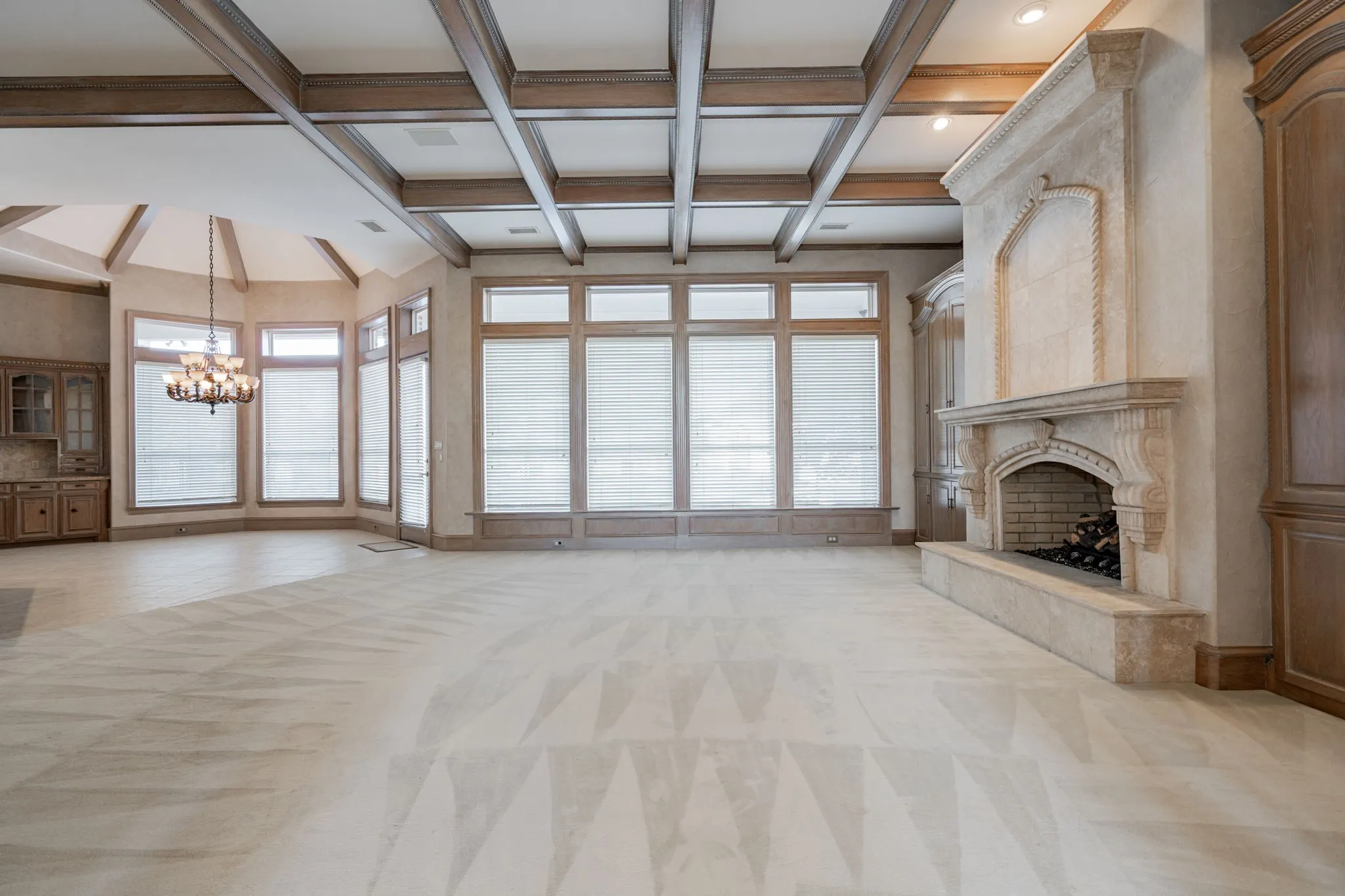 Unfurnished living room with beam ceiling, light colored carpet, a premium fireplace, a chandelier, and healthy amount of natural light