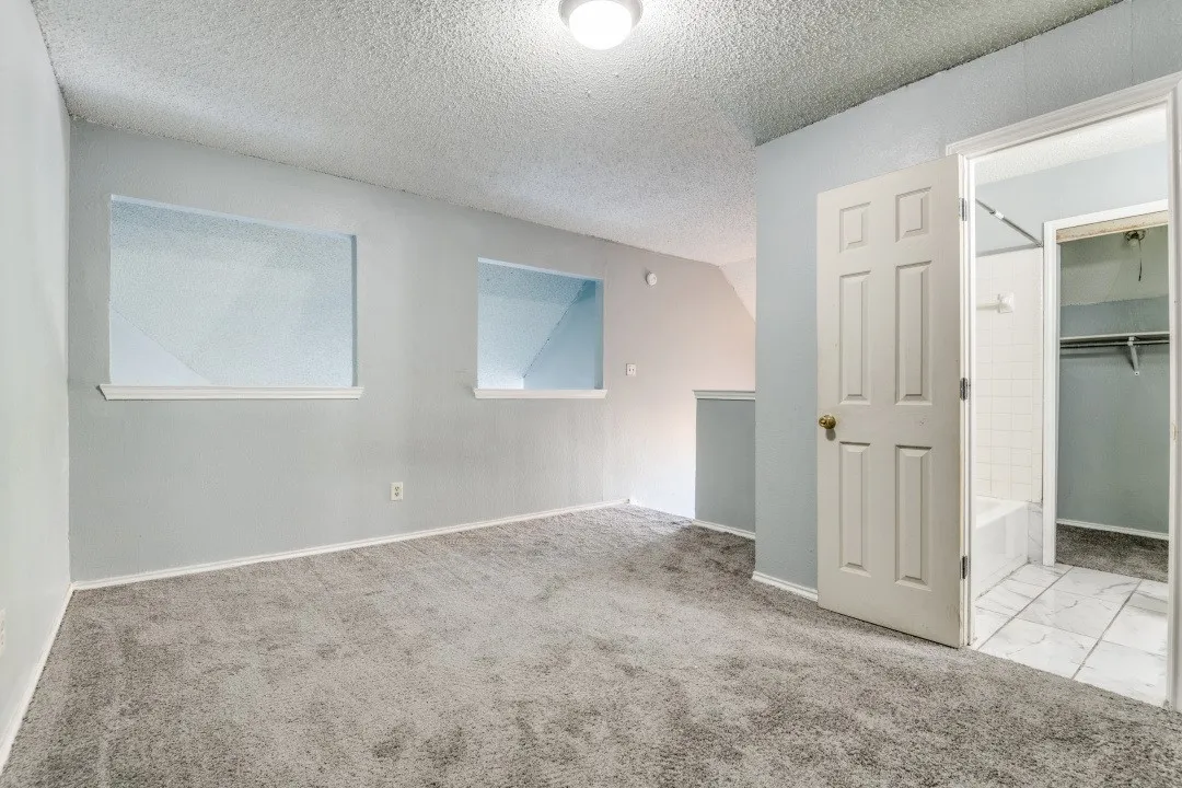 Carpeted empty room featuring baseboards and a textured ceiling