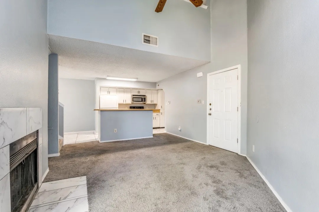 Unfurnished living room featuring baseboards, visible vents, a fireplace, a textured ceiling, and light carpet