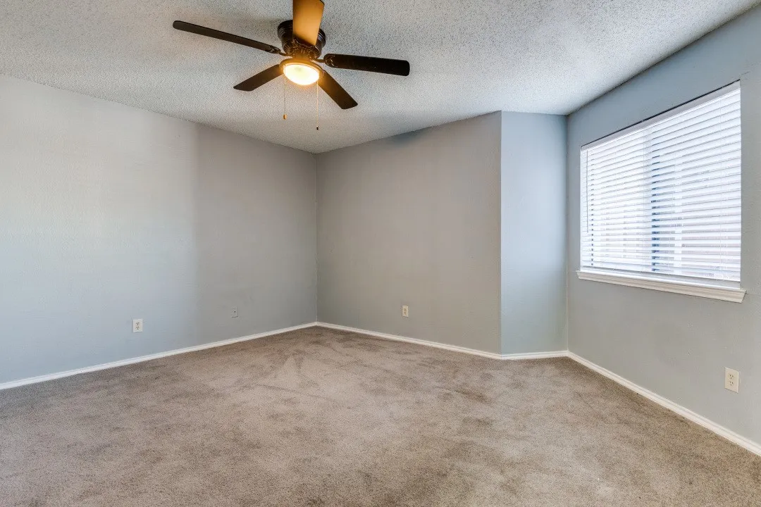 Carpeted spare room featuring a textured ceiling, baseboards, and ceiling fan