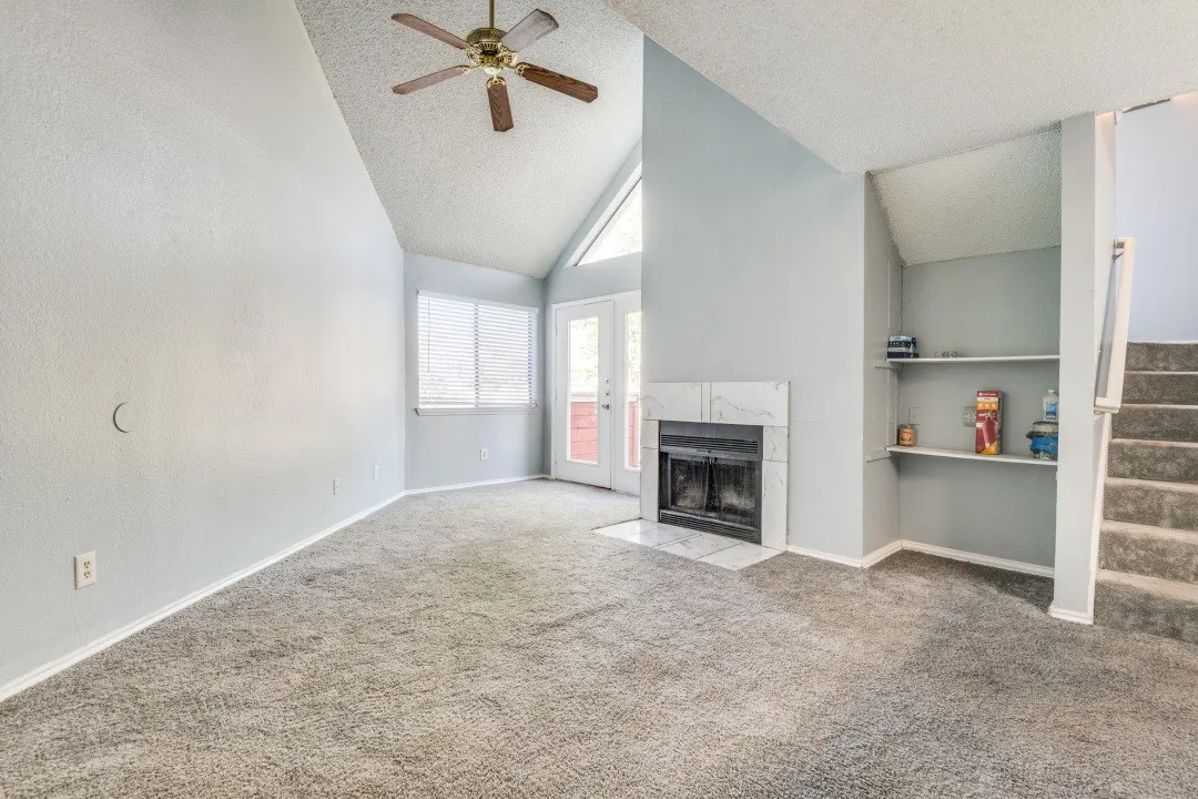 Unfurnished living room with a ceiling fan, a textured ceiling, stairway, carpet, and a premium fireplace