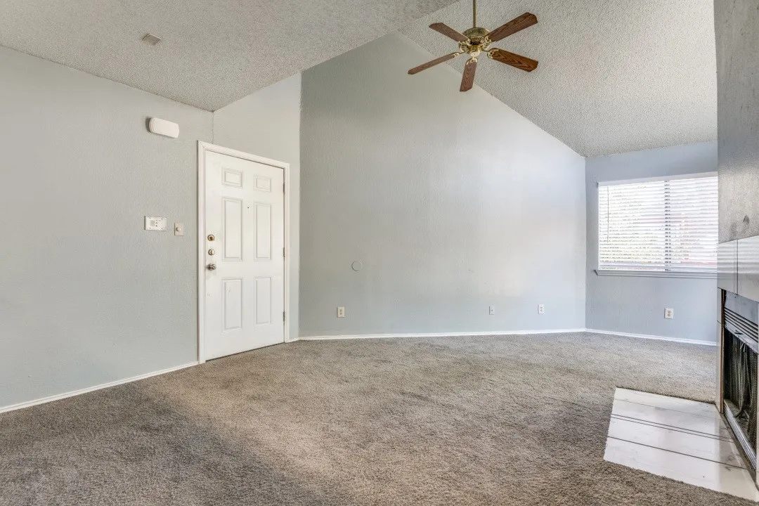 Unfurnished living room featuring a textured ceiling, carpet flooring, and ceiling fan