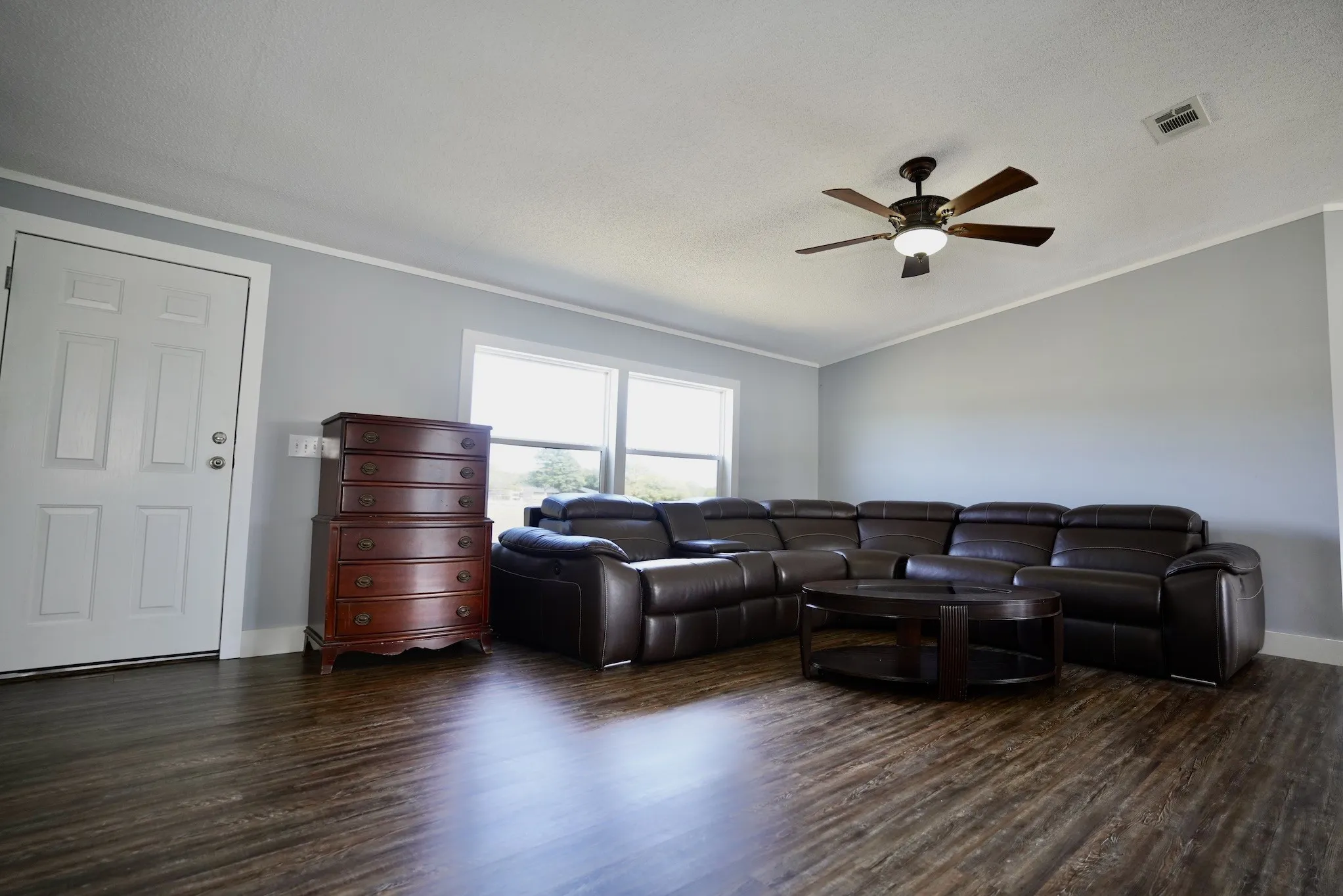 Living area with dark wood-type flooring, crown molding, vaulted ceiling, and a ceiling fan