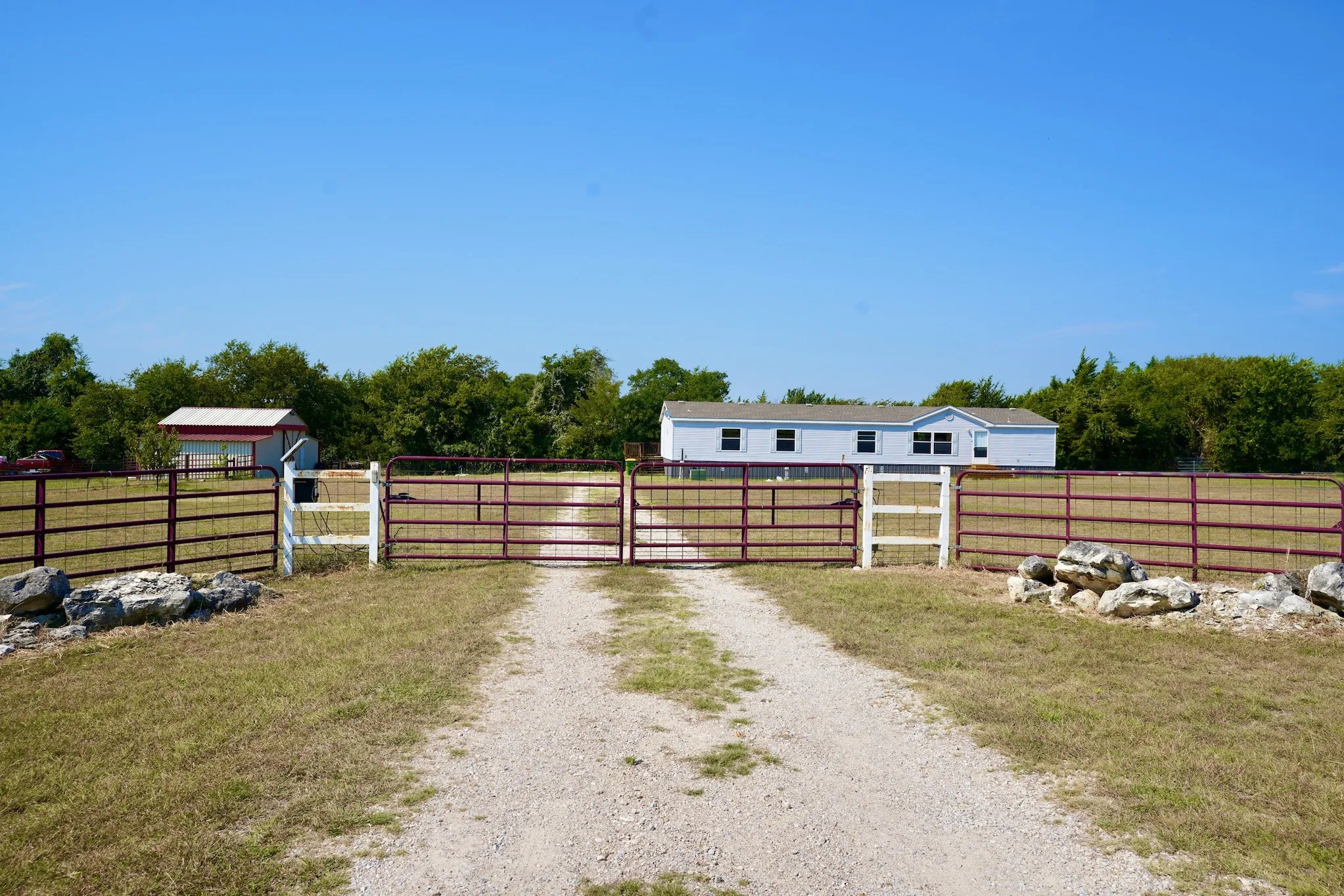 View of dirt / gravel driveway featuring a gate and a gated entry