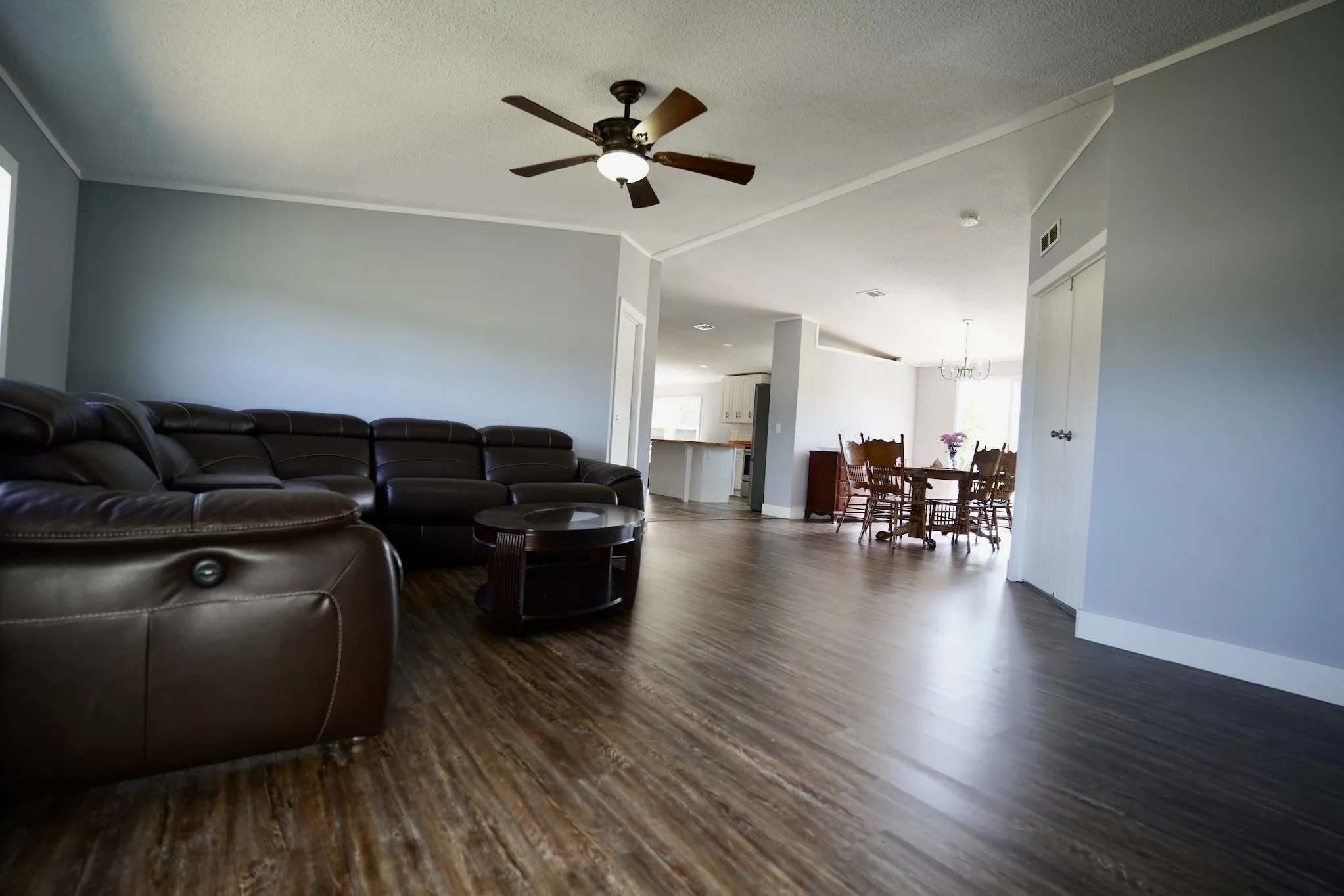 Living area with dark wood-style floors, a ceiling fan, a textured ceiling, a chandelier, and ornamental molding