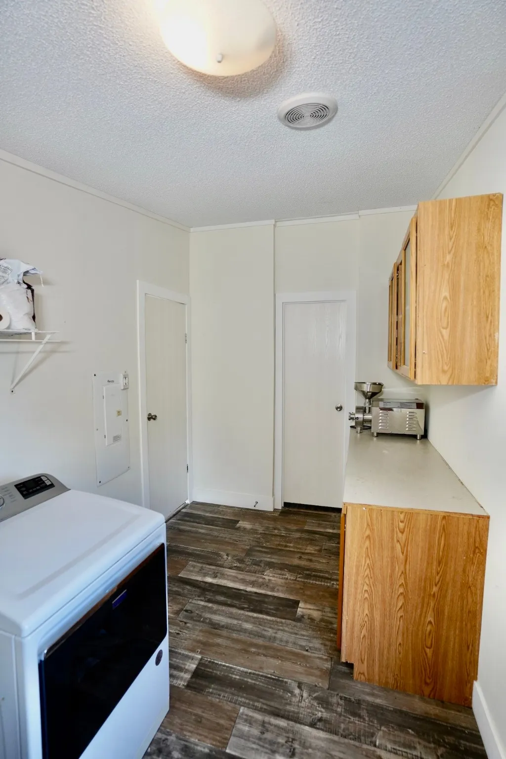 Laundry area featuring washer / dryer, a textured ceiling, and dark wood-type flooring