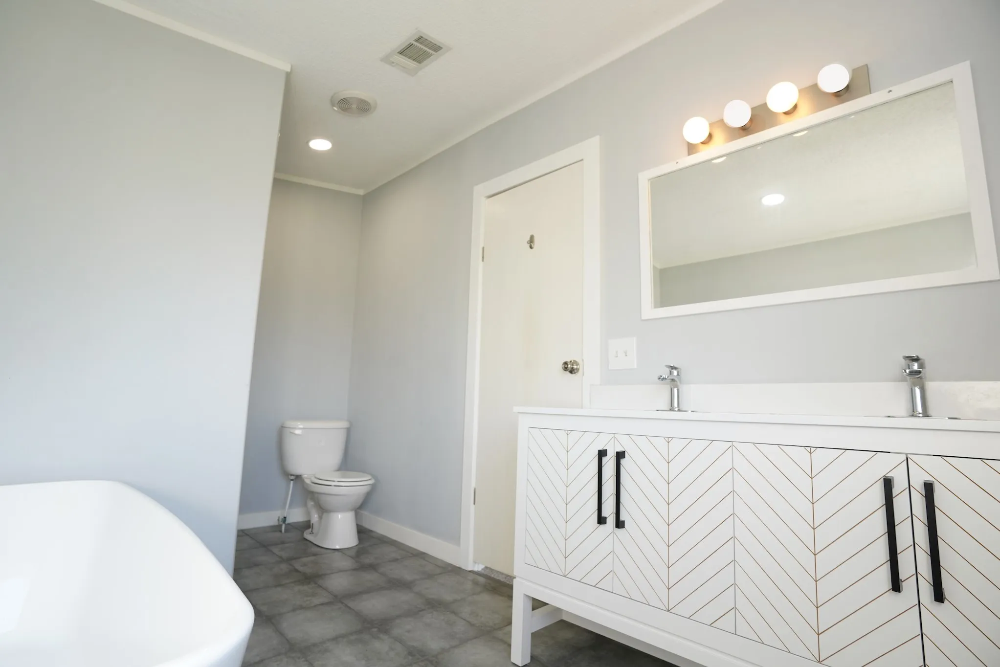 Full bathroom featuring a soaking tub, double vanity, and recessed lighting