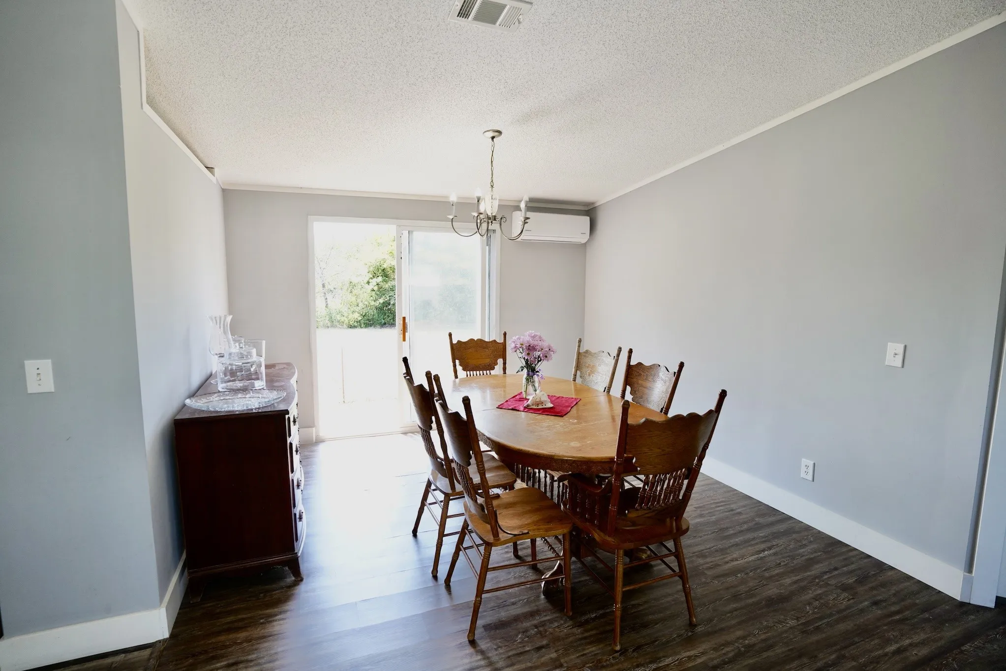 Dining area with dark wood finished floors, a chandelier, ornamental molding, a textured ceiling, and a wall mounted air conditioner