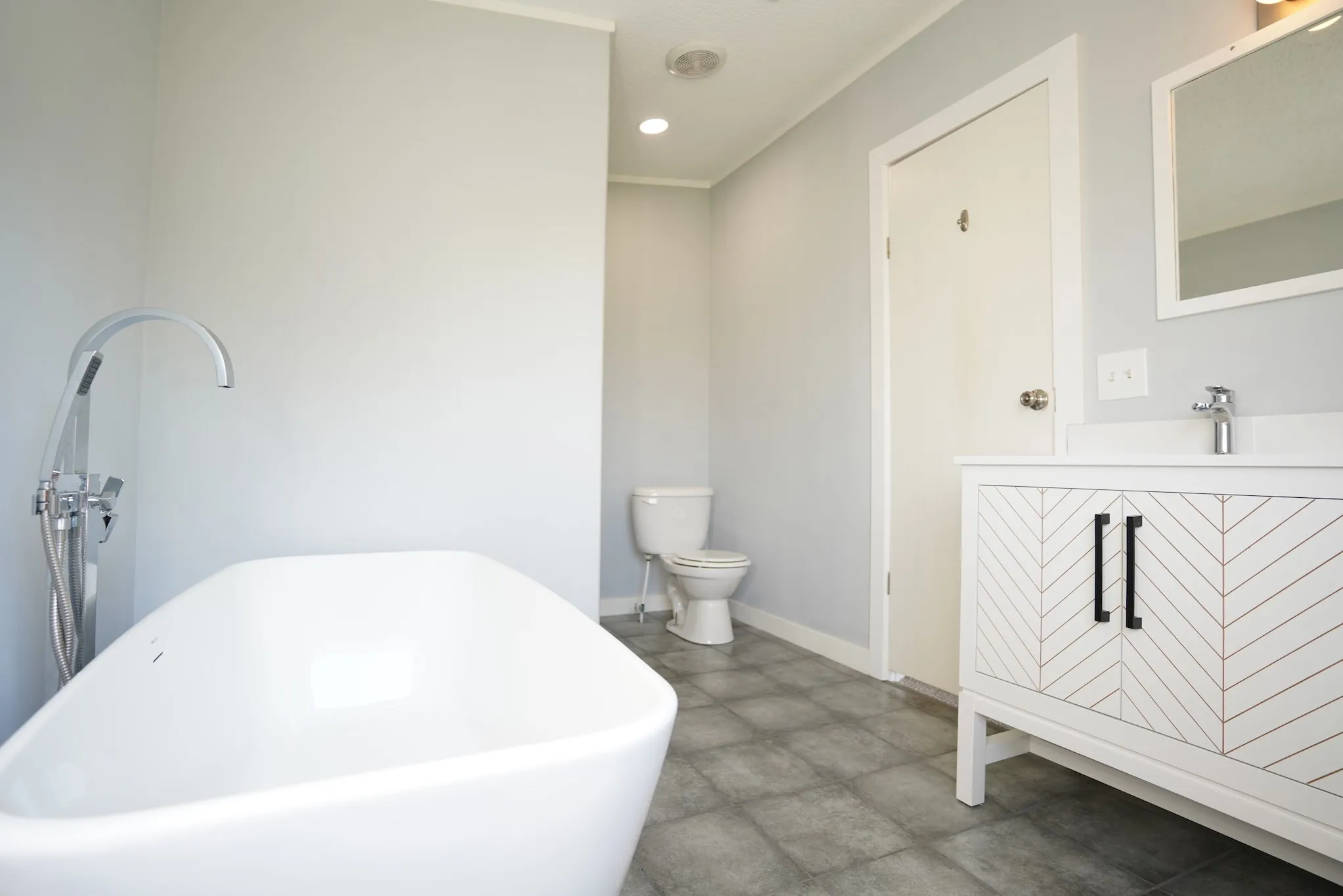Full bath featuring a freestanding bath, vanity, and recessed lighting