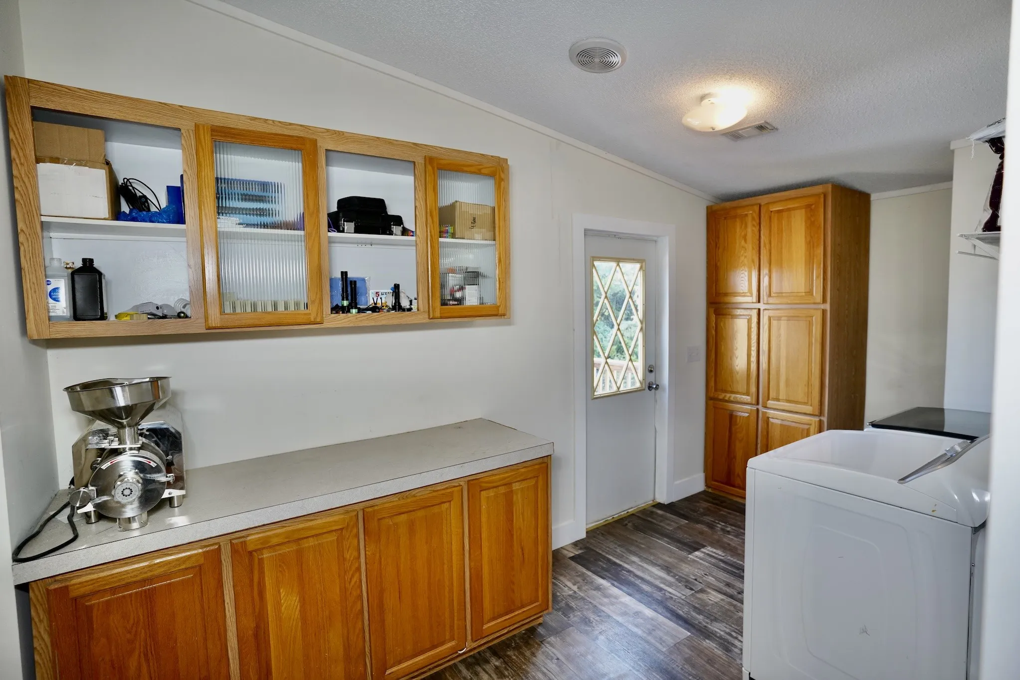 Washroom featuring dark wood finished floors, a textured ceiling, cabinet space, and crown molding