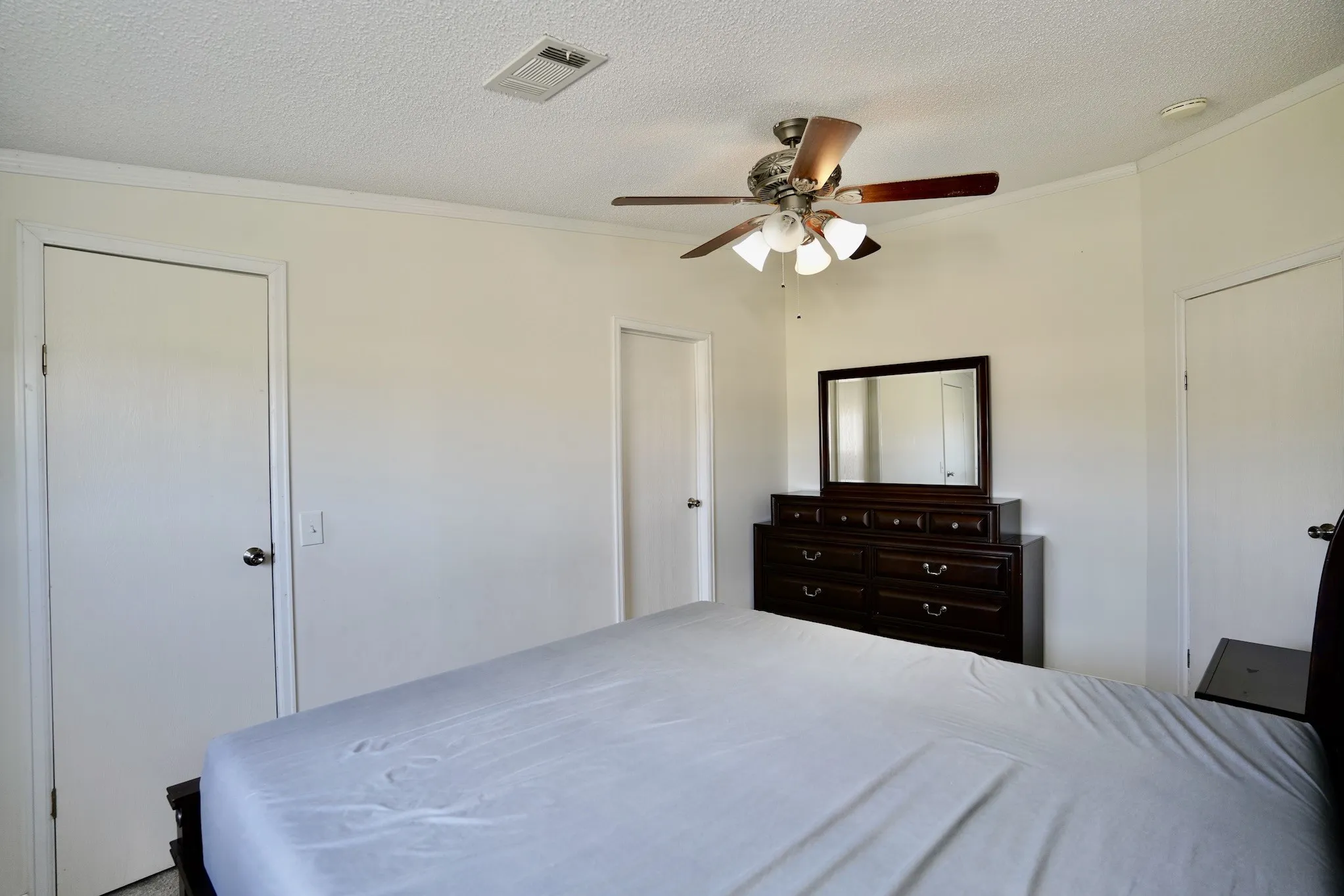 Bedroom featuring a textured ceiling, crown molding, and ceiling fan