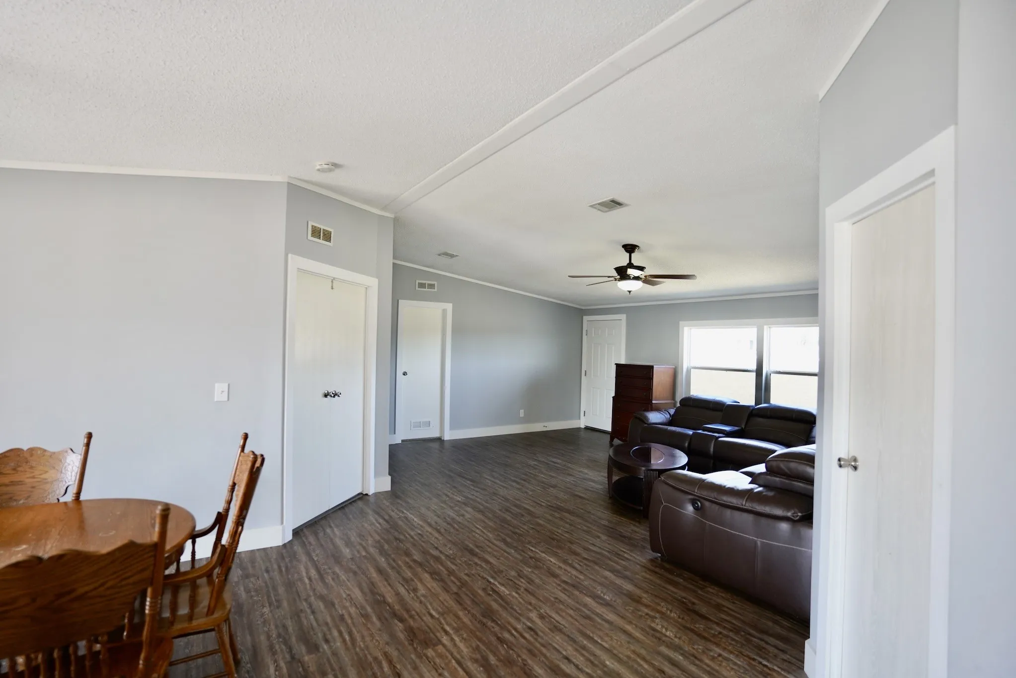 Living area featuring ornamental molding, dark wood-type flooring, vaulted ceiling, and ceiling fan