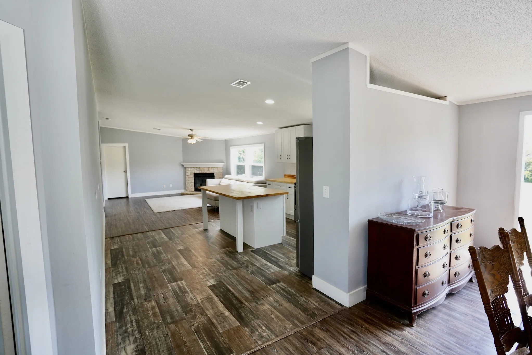 Kitchen with white cabinets, a brick fireplace, dark wood-style flooring, open floor plan, and crown molding
