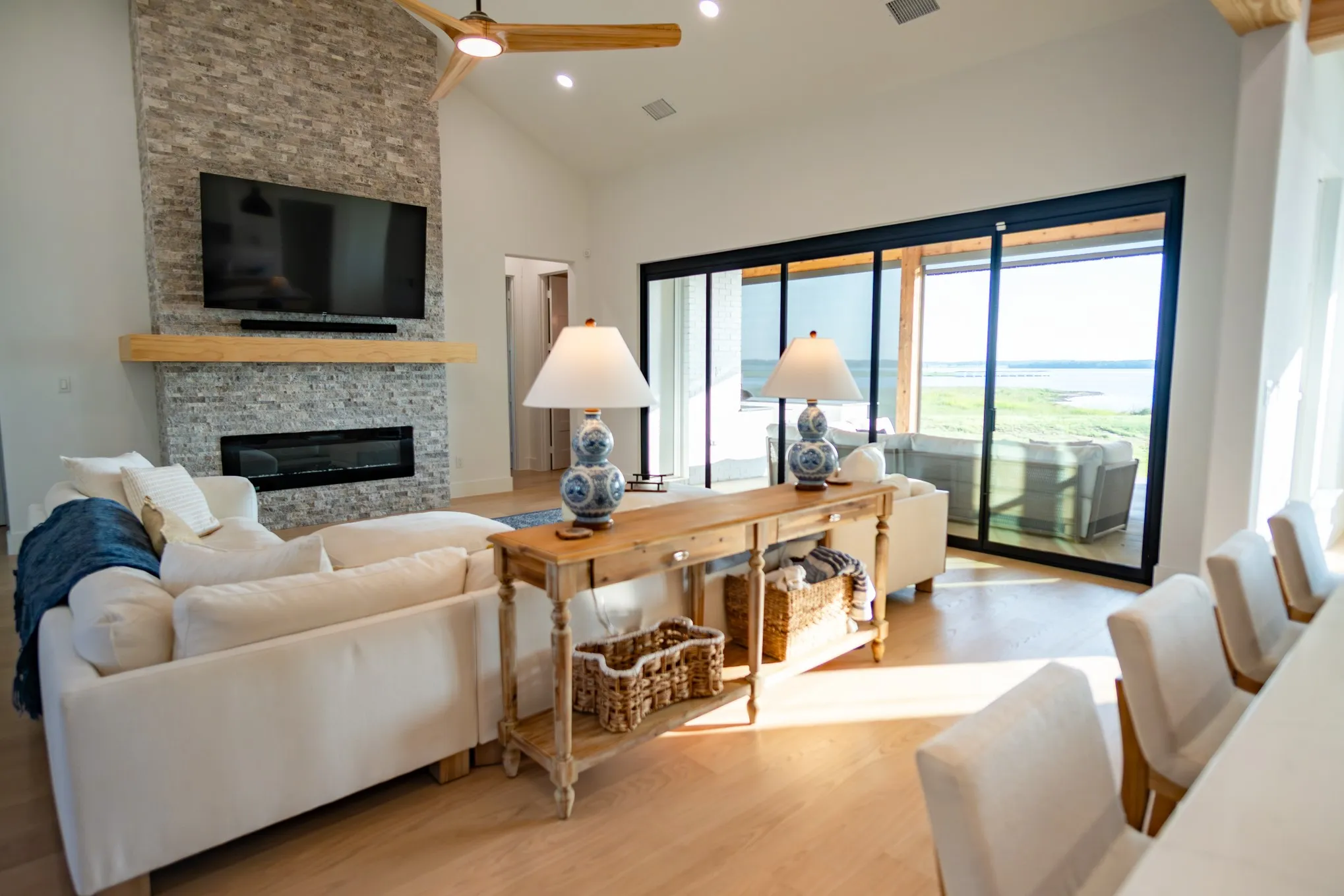 Living area with a fireplace, wood finished floors, high vaulted ceiling, recessed lighting, and a ceiling fan