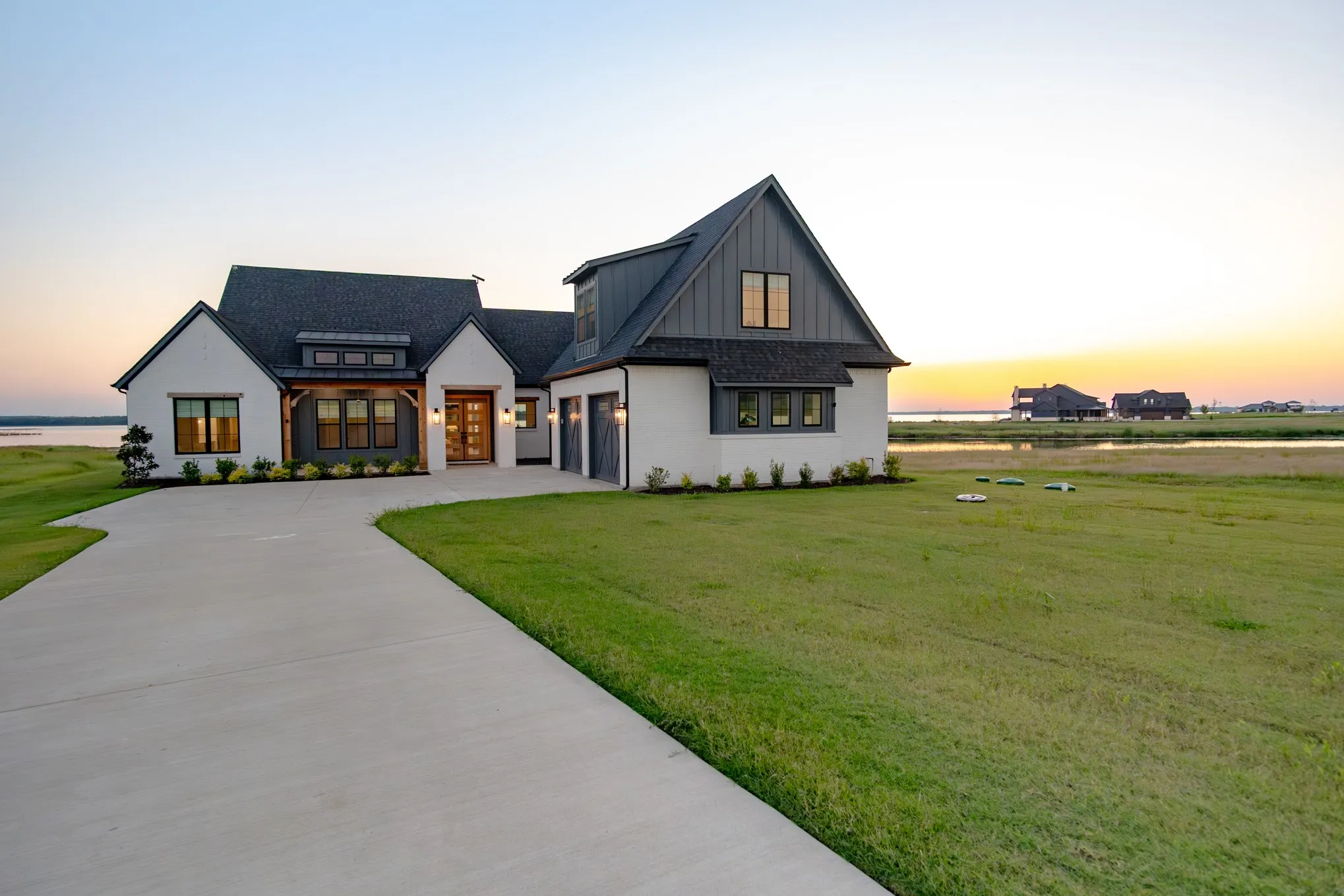 Modern inspired farmhouse featuring concrete driveway, board and batten siding, a front yard, a garage, and roof with shingles