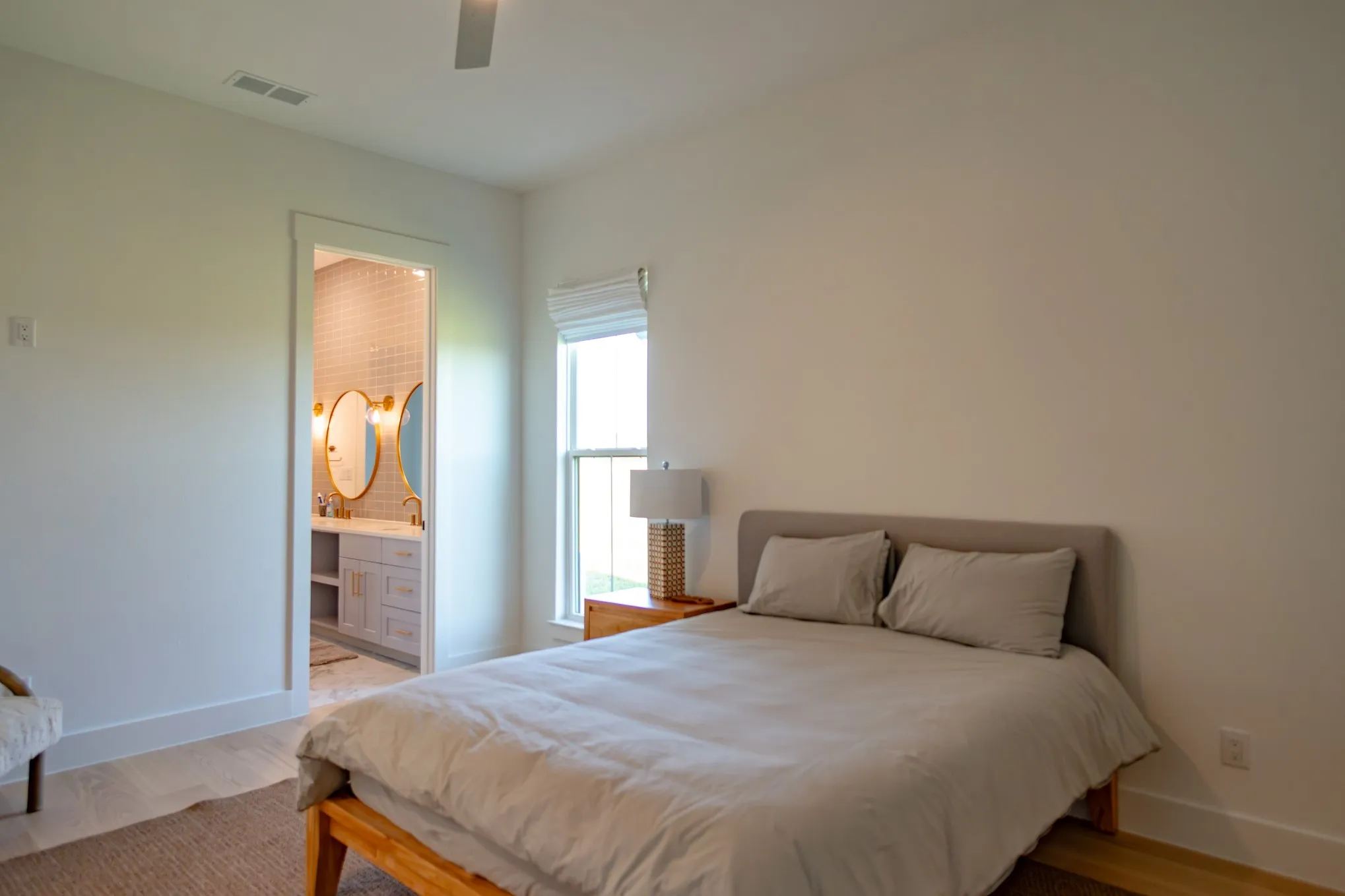 Bedroom with light wood-style floors, connected bathroom, and ceiling fan