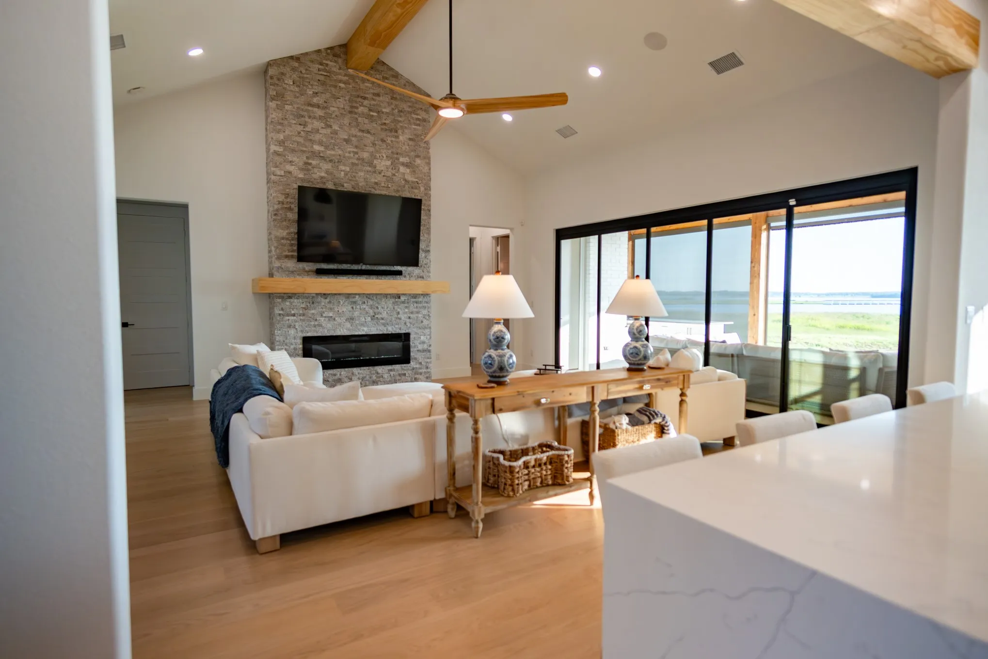 Living room featuring beam ceiling, a fireplace, light wood-style flooring, high vaulted ceiling, and recessed lighting