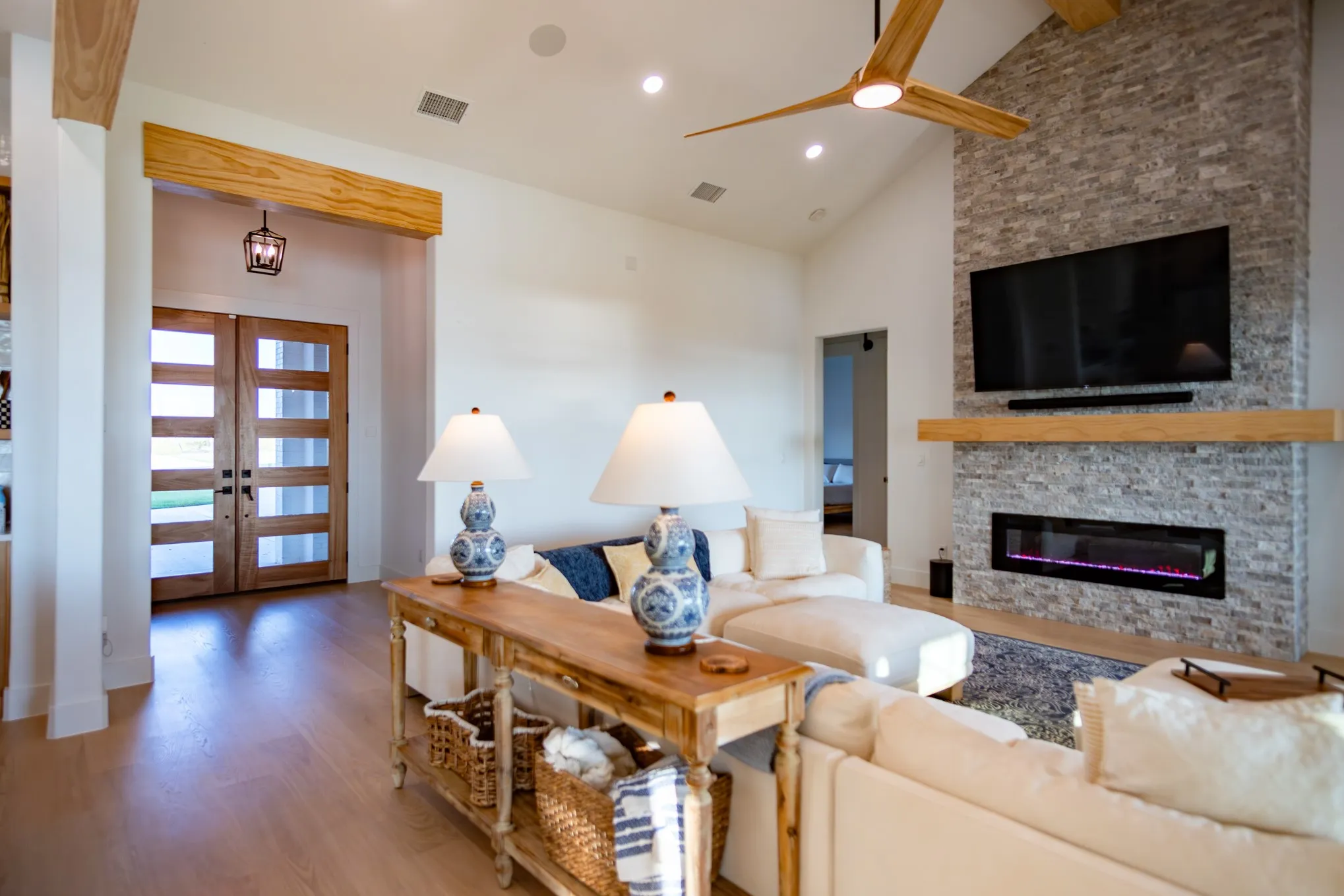Living area featuring light wood-style flooring, high vaulted ceiling, a fireplace, recessed lighting, and a ceiling fan