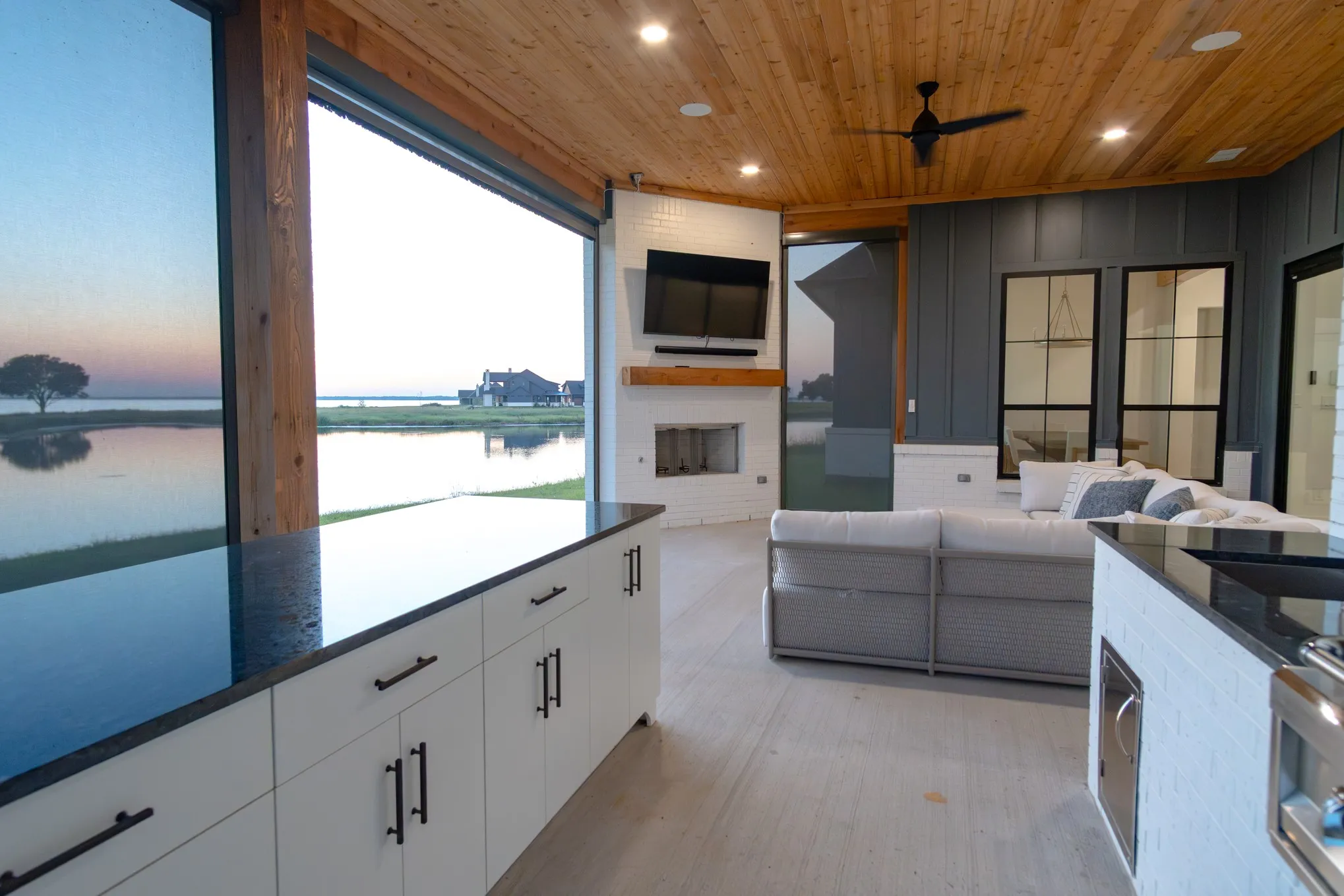 View of patio with a water view, an outdoor living space with a fireplace, and a ceiling fan
