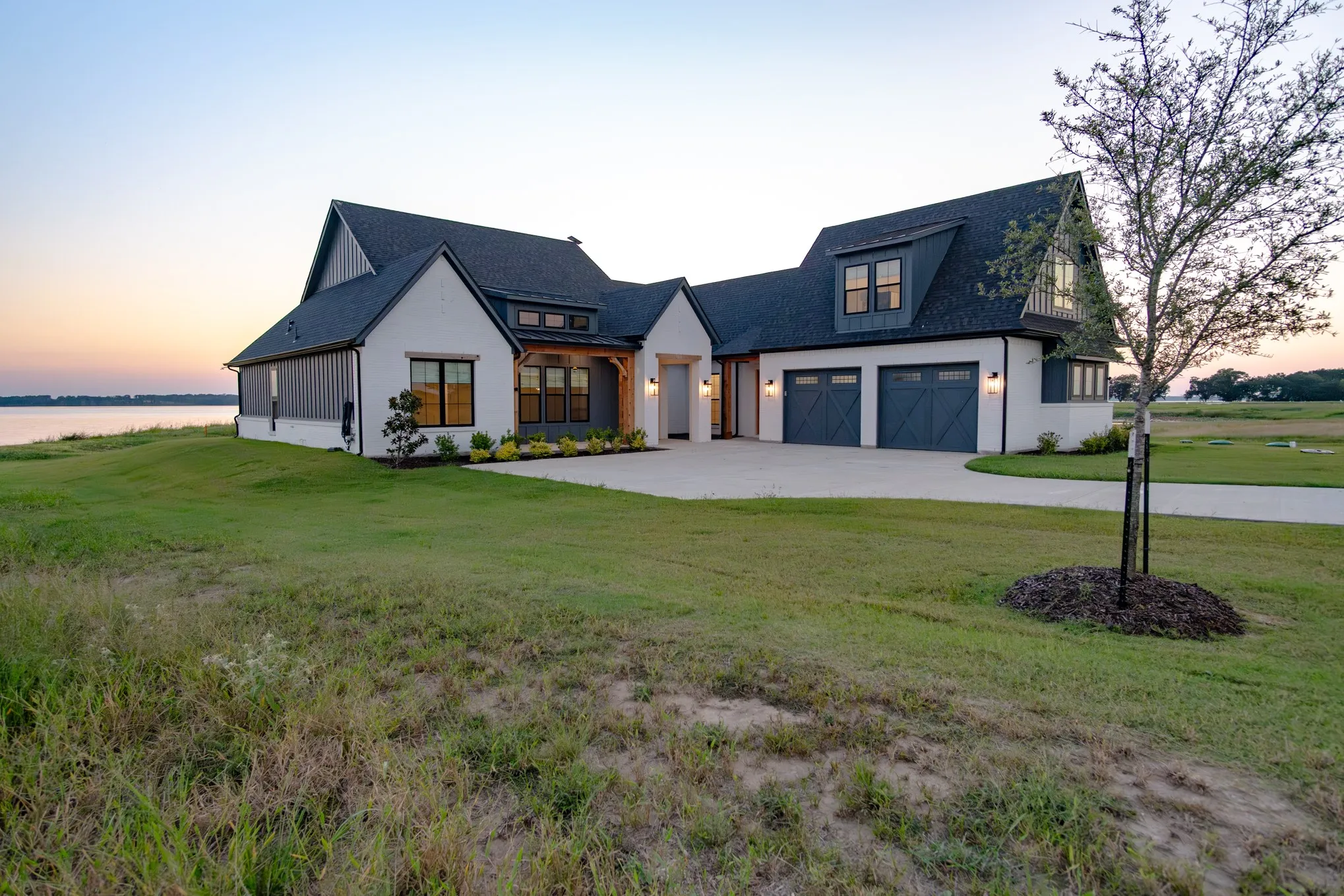 Modern farmhouse with concrete driveway, a front lawn, and a garage