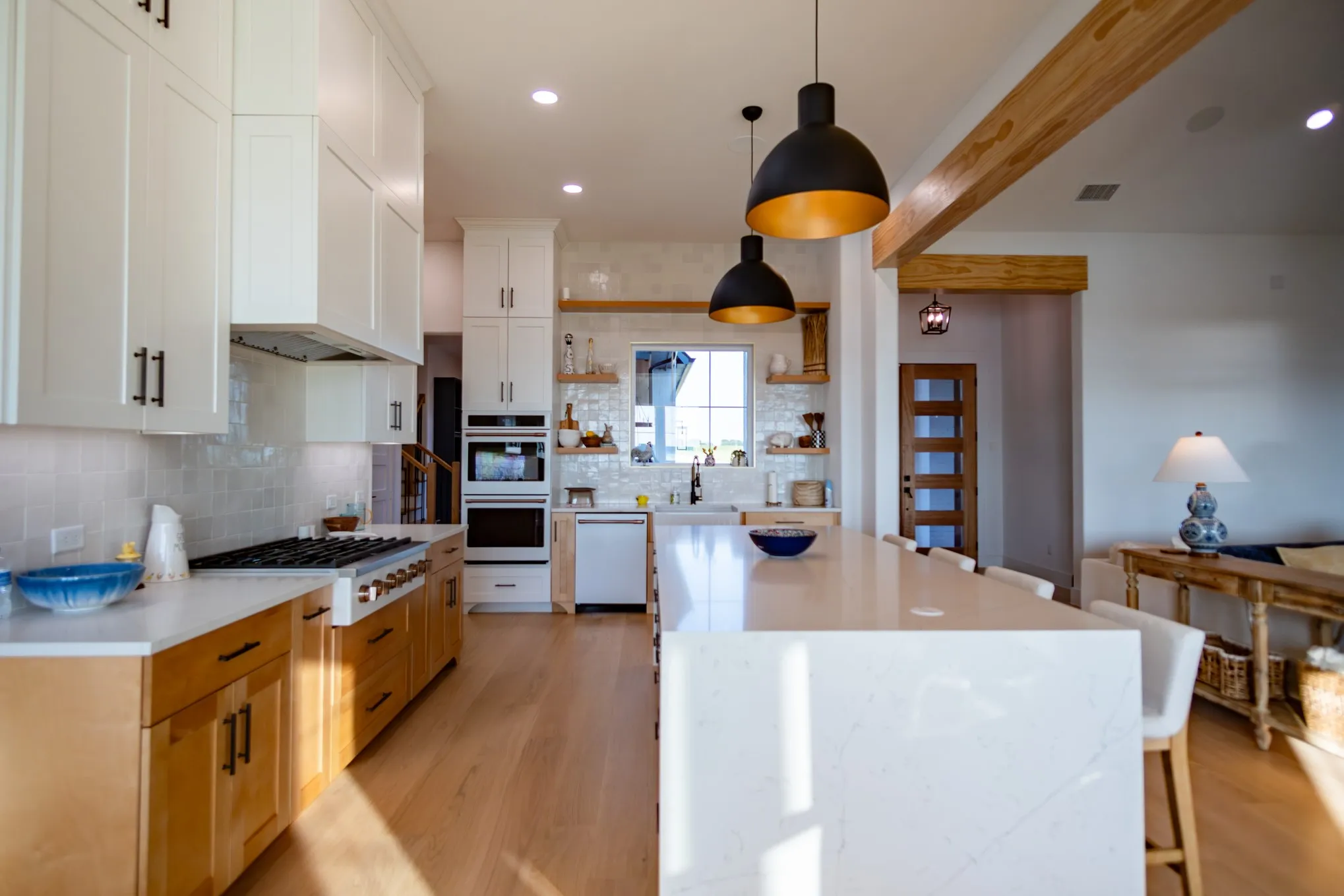 Kitchen with open shelves, light wood-style flooring, backsplash, a breakfast bar, and decorative light fixtures