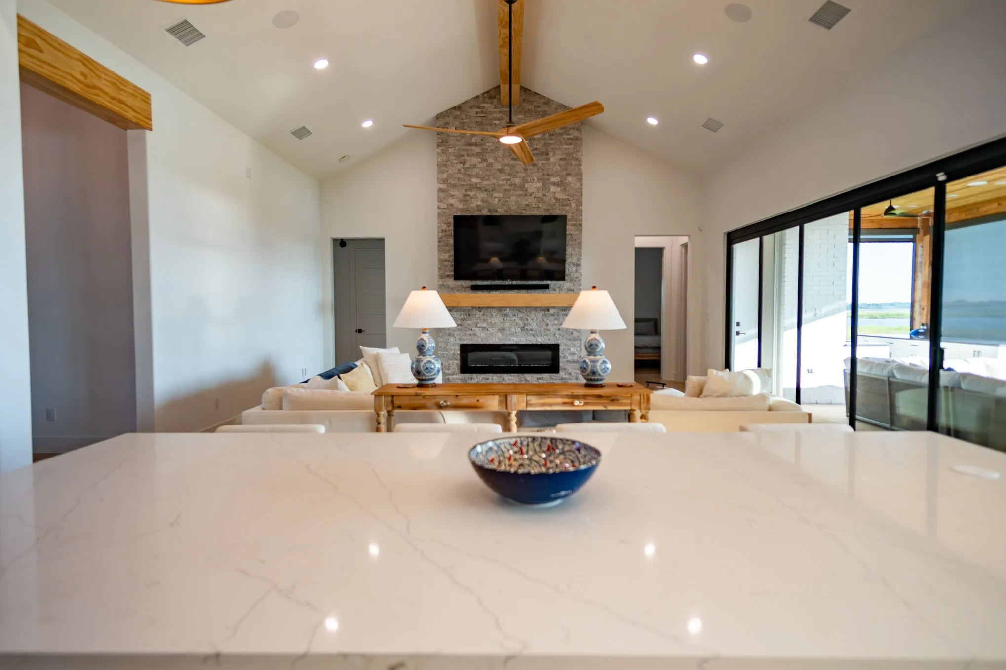 Kitchen featuring beam ceiling, light stone counters, a fireplace, open floor plan, and high vaulted ceiling
