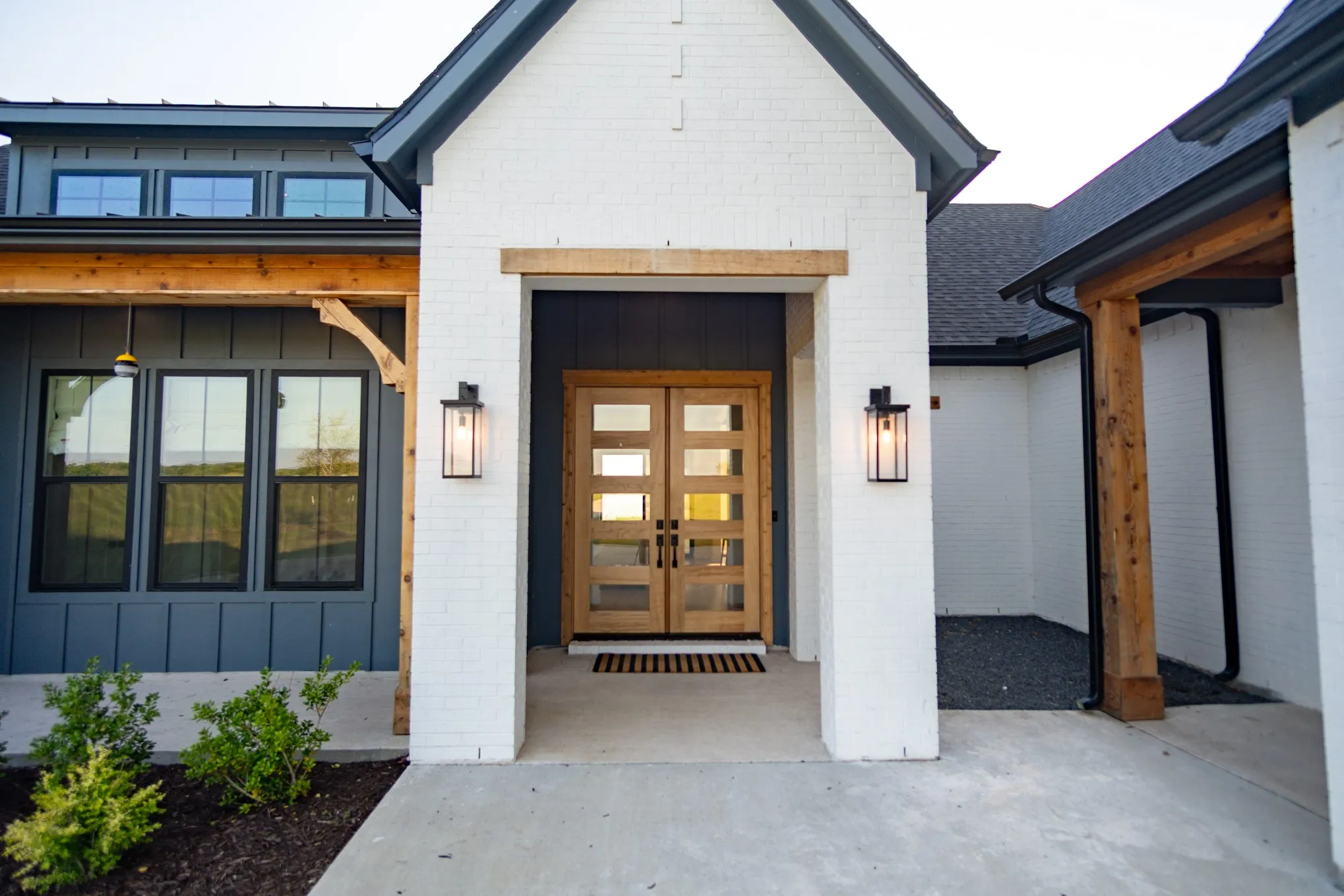 Property entrance with board and batten siding, brick siding, and french doors