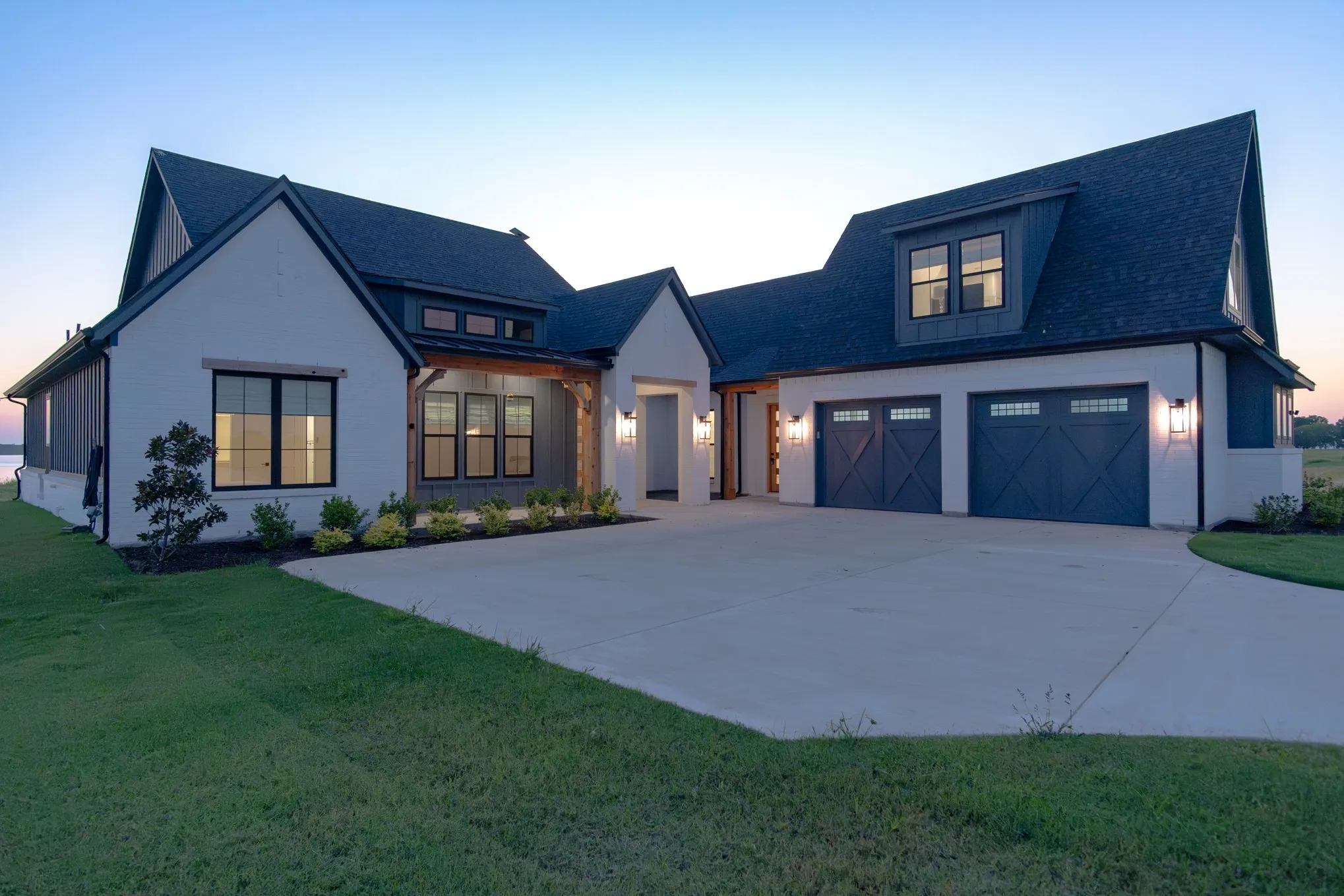 Modern inspired farmhouse with a garage, driveway, a shingled roof, and a yard