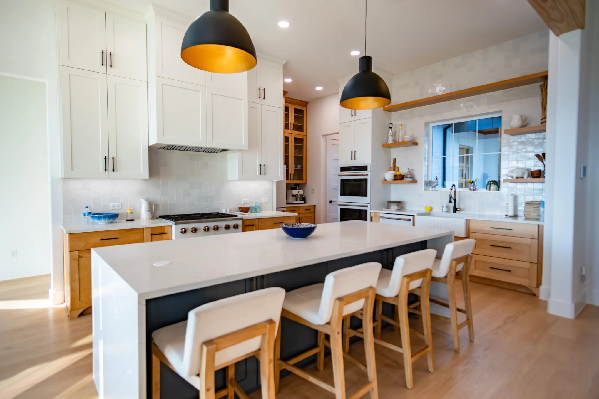 Kitchen with backsplash, white cabinets, light wood-style floors, light stone counters, and open shelves