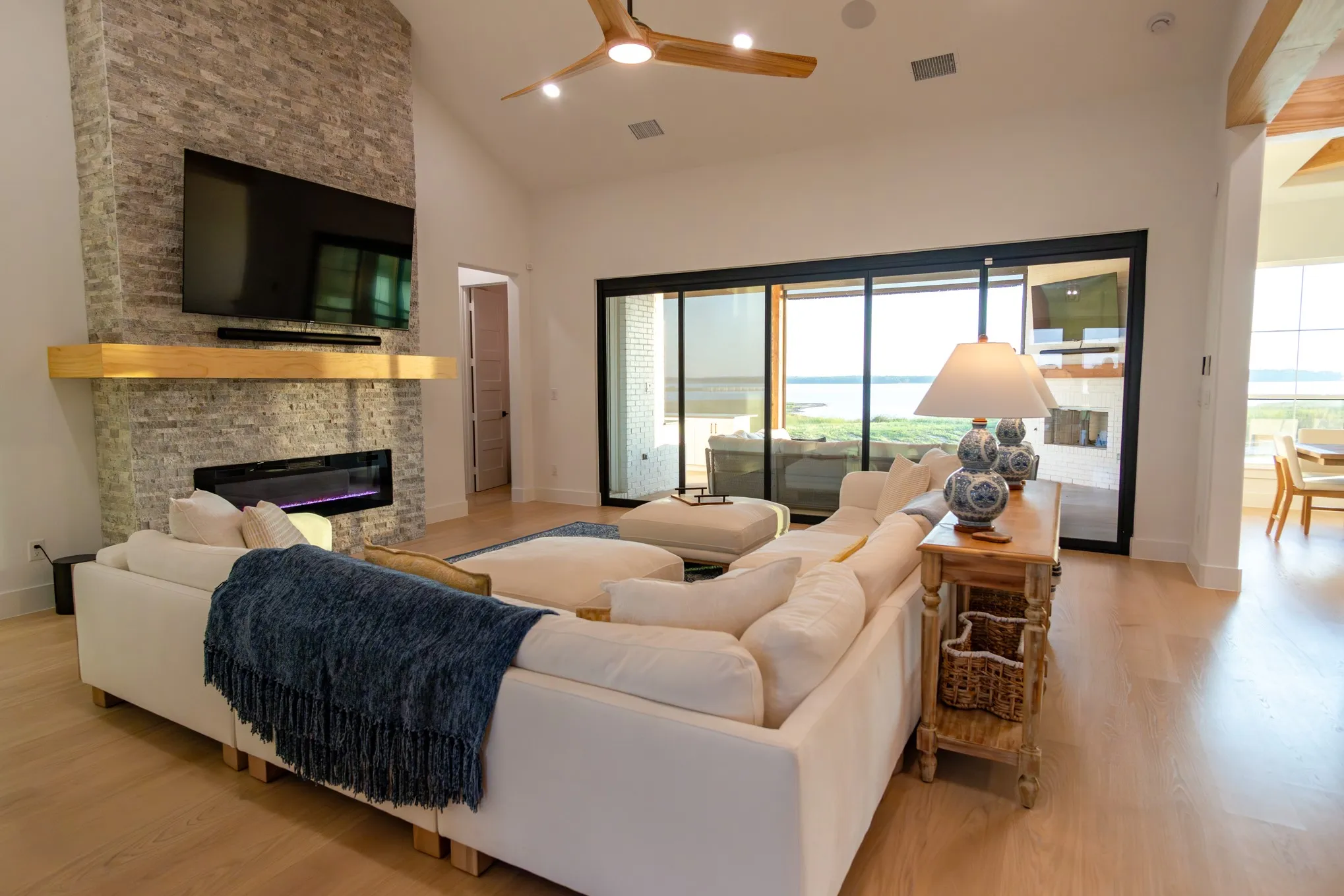 Living area featuring high vaulted ceiling, a fireplace, light wood-style floors, a ceiling fan, and recessed lighting