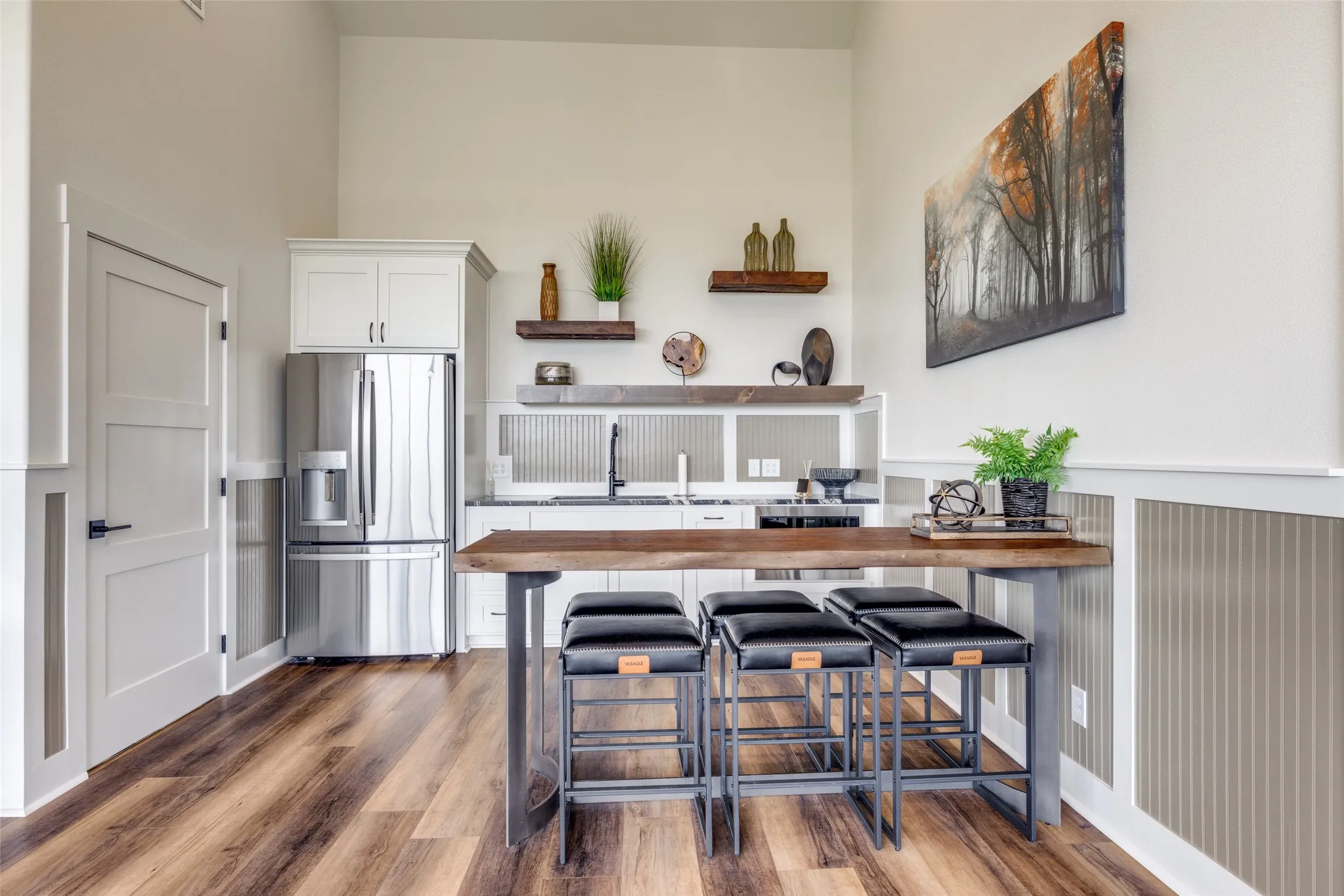 Kitchen with white cabinets, open shelves, a breakfast bar, stainless steel fridge, and butcher block countertops