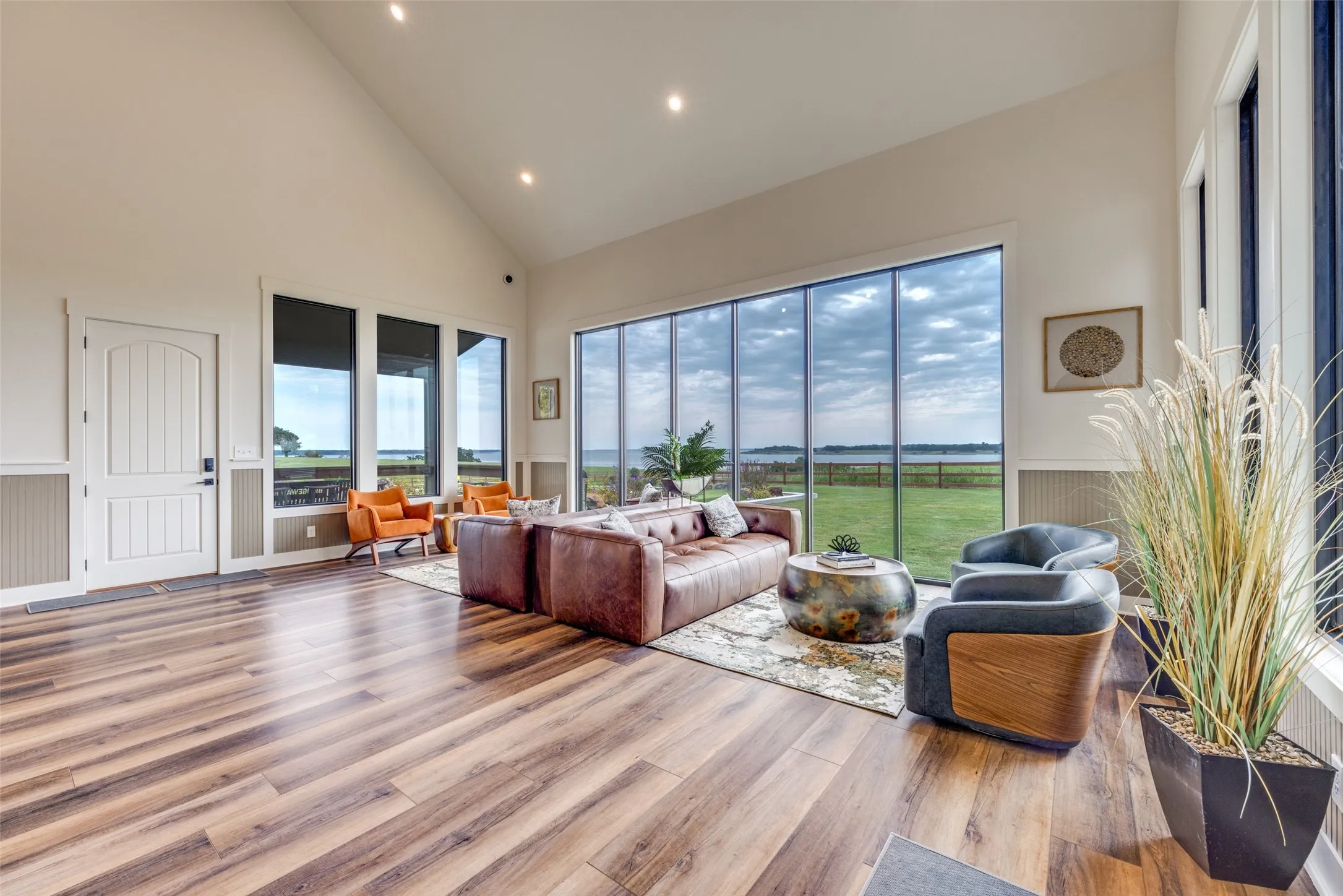 Living area featuring high vaulted ceiling, wainscoting, light wood-style floors, and recessed lighting